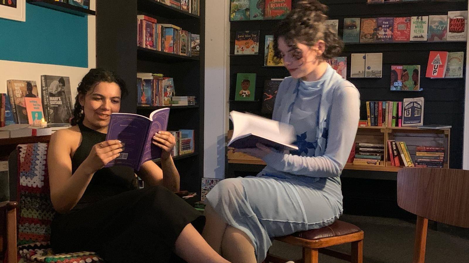 Candid photo of Karishma Natu and Victoria Grant sat in Bookbag, holding copies of 'Beneath The Blue'.