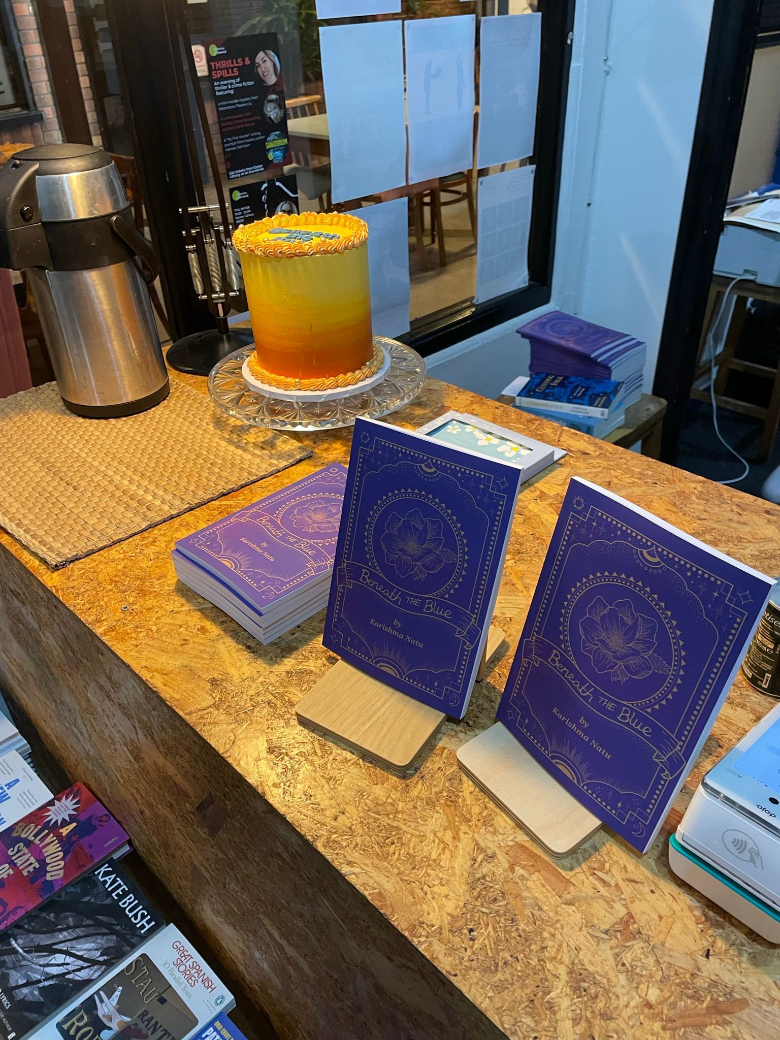 A table at Bookbag with Karishma's book and a tall, sunset-gradient cake.