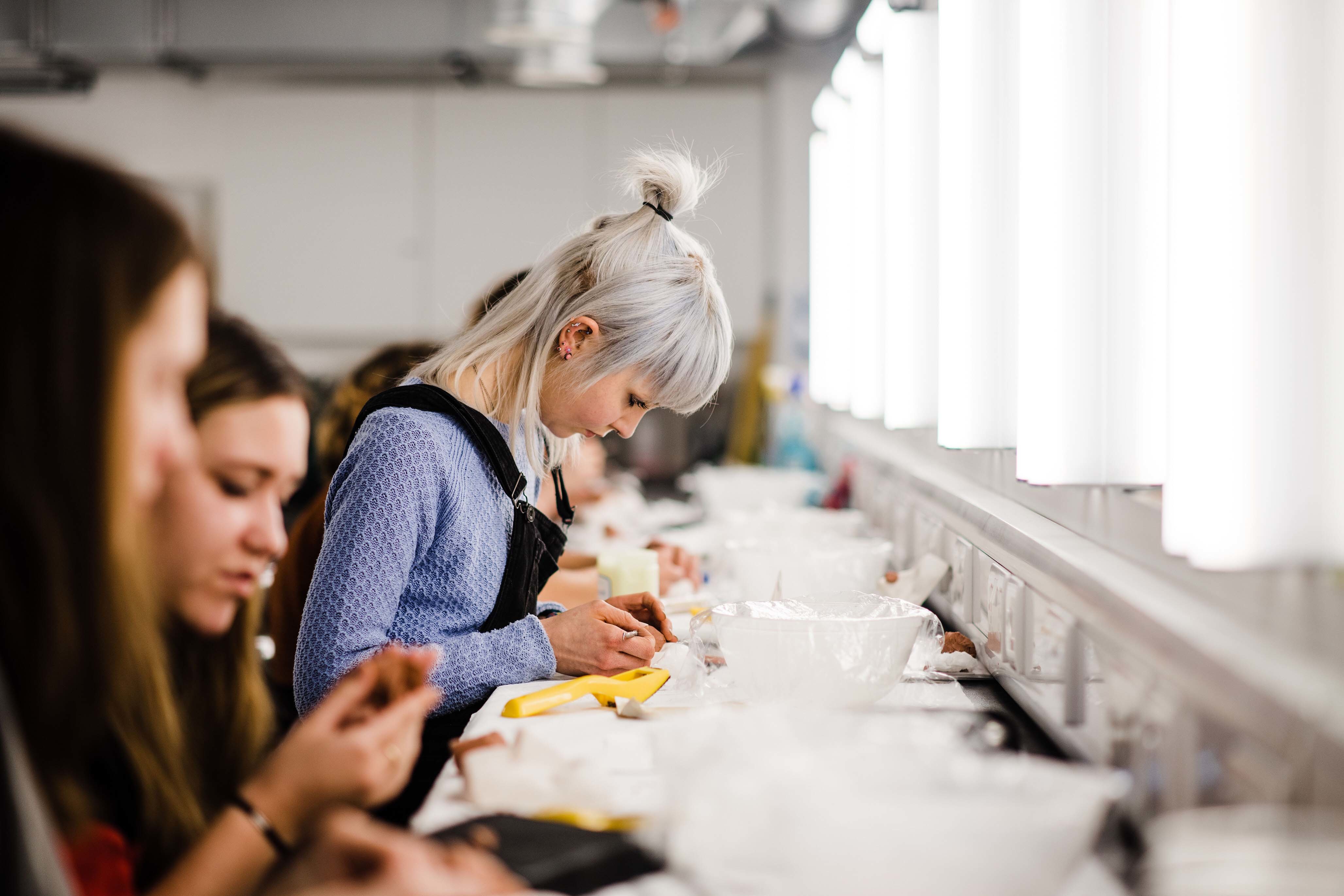 Students working at a long table in a makeup studio.