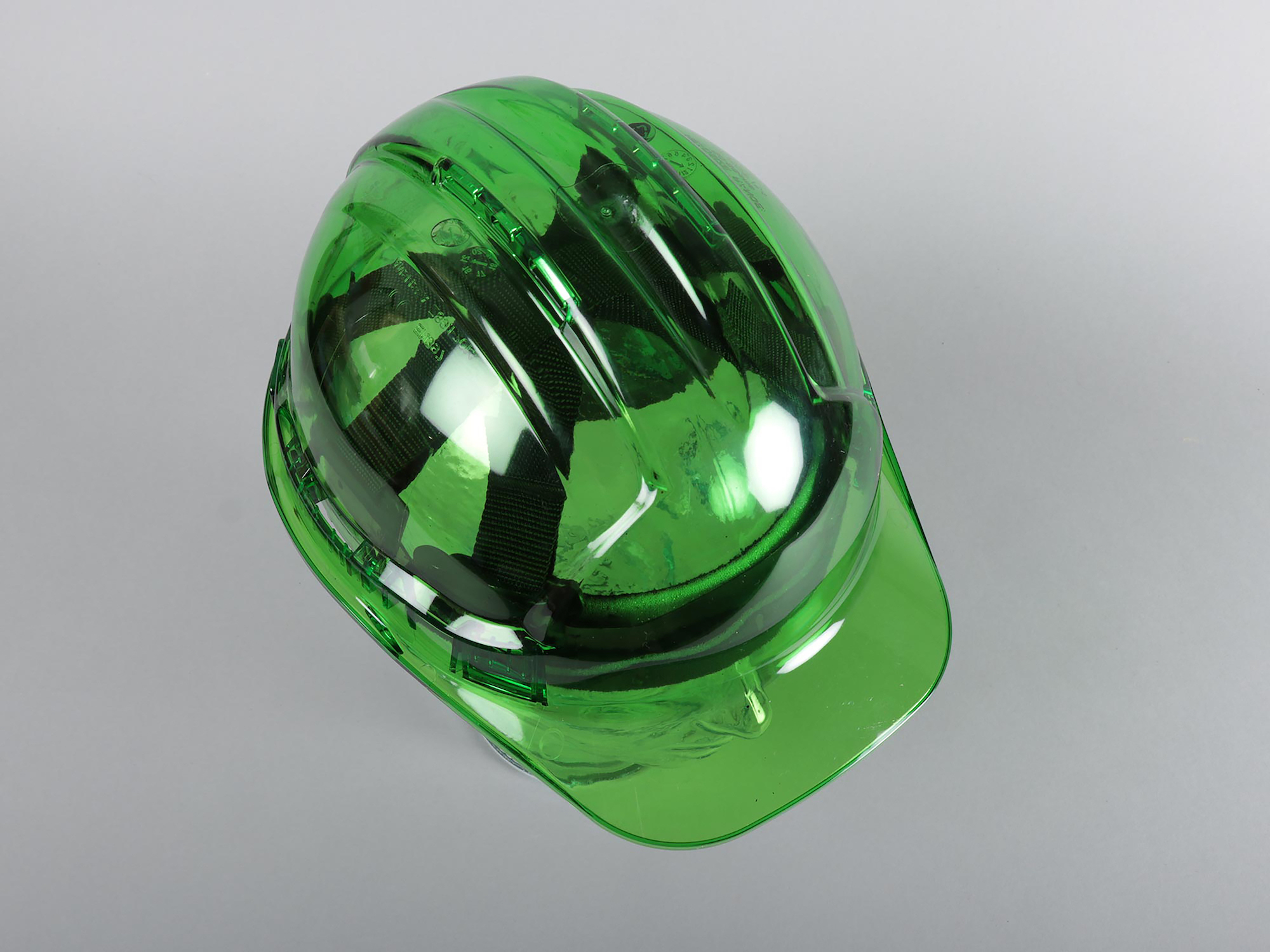 A green plastic helmet on a plain grey background.
