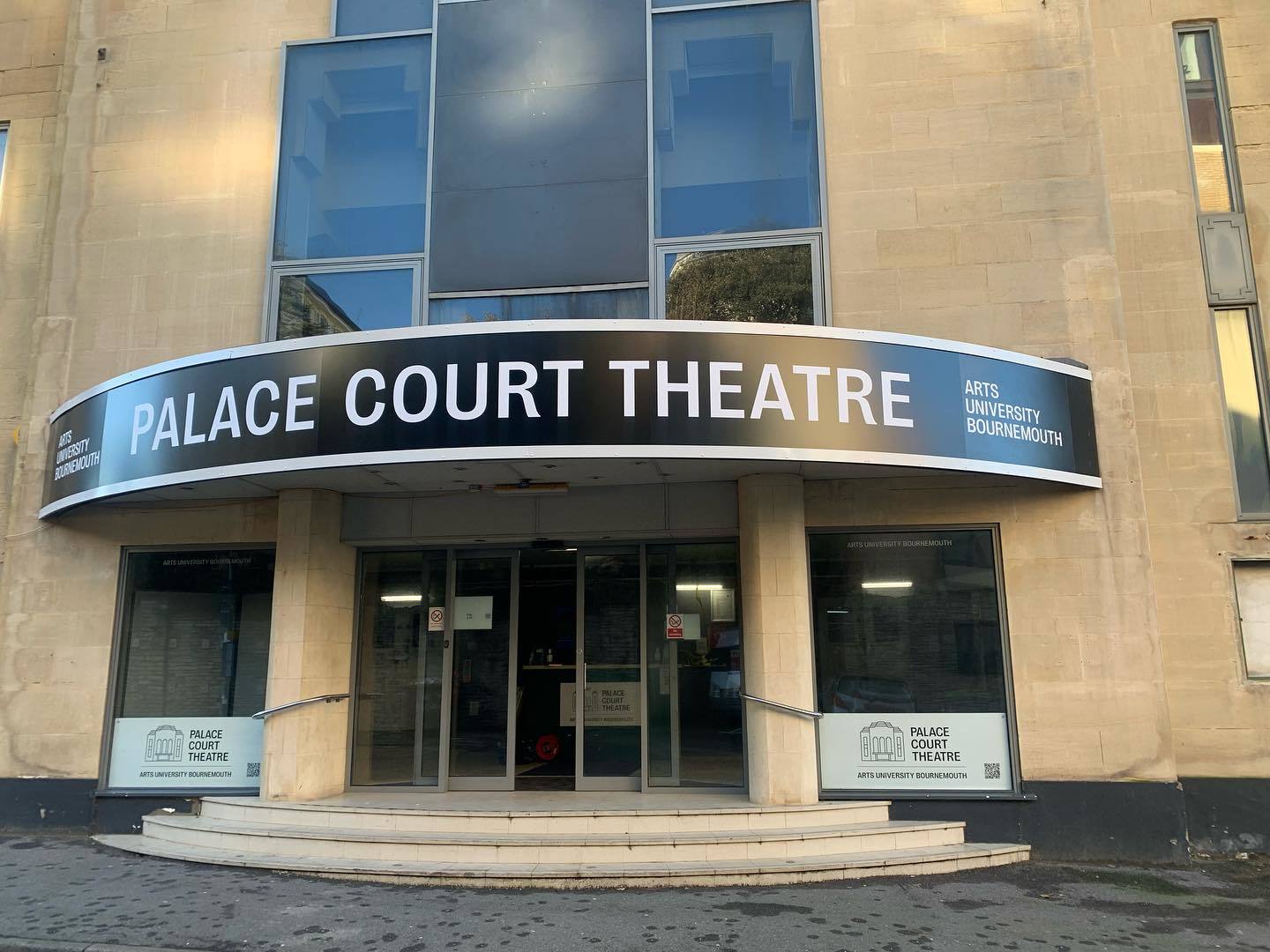 Exterior of the Palace Court Theatre in Bournemouth, with a large black banner sign and white text above it.
