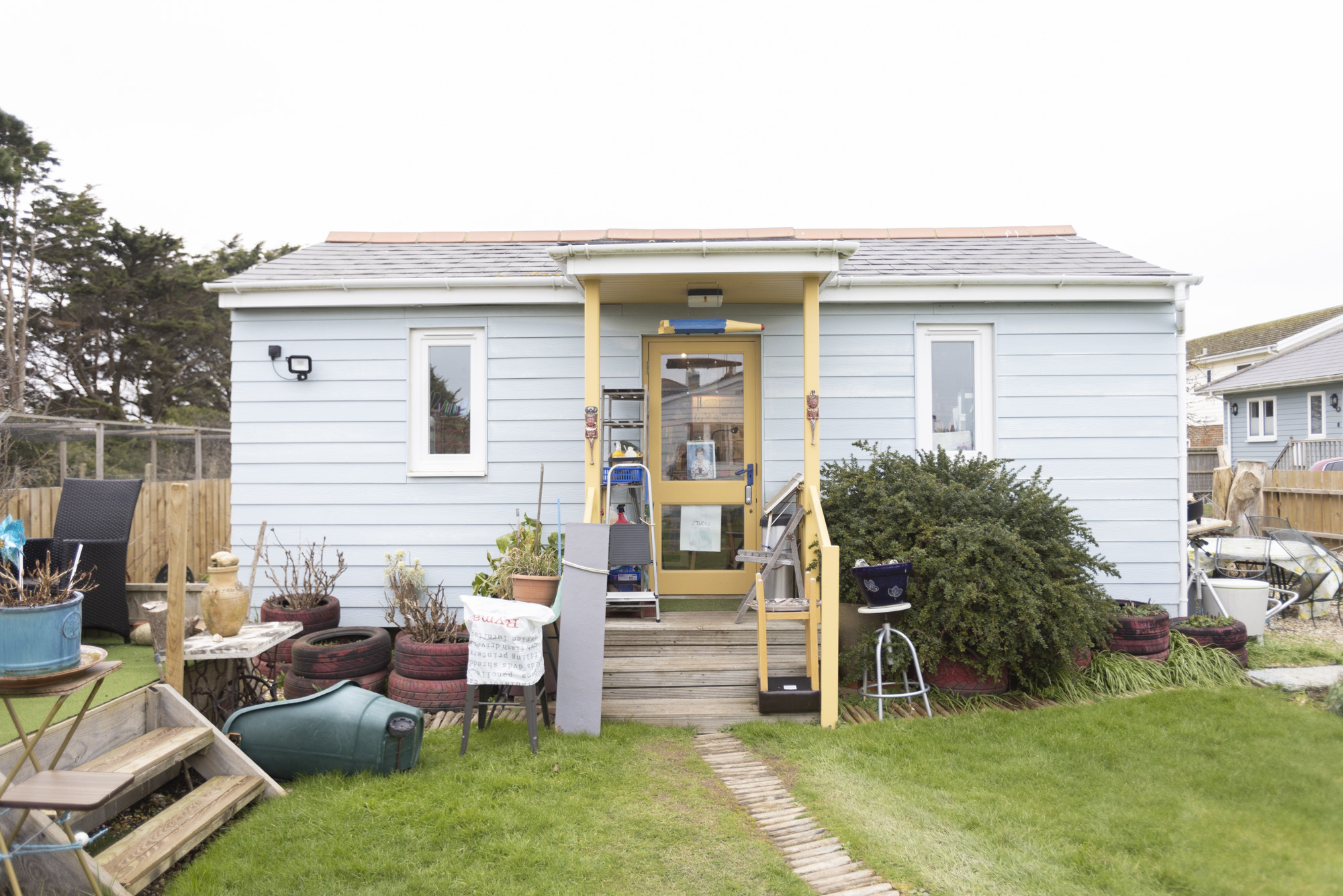 Pamela Howard's studio, an outdoor home in blue with a yellow entrance frame and a model pencil hanging above.