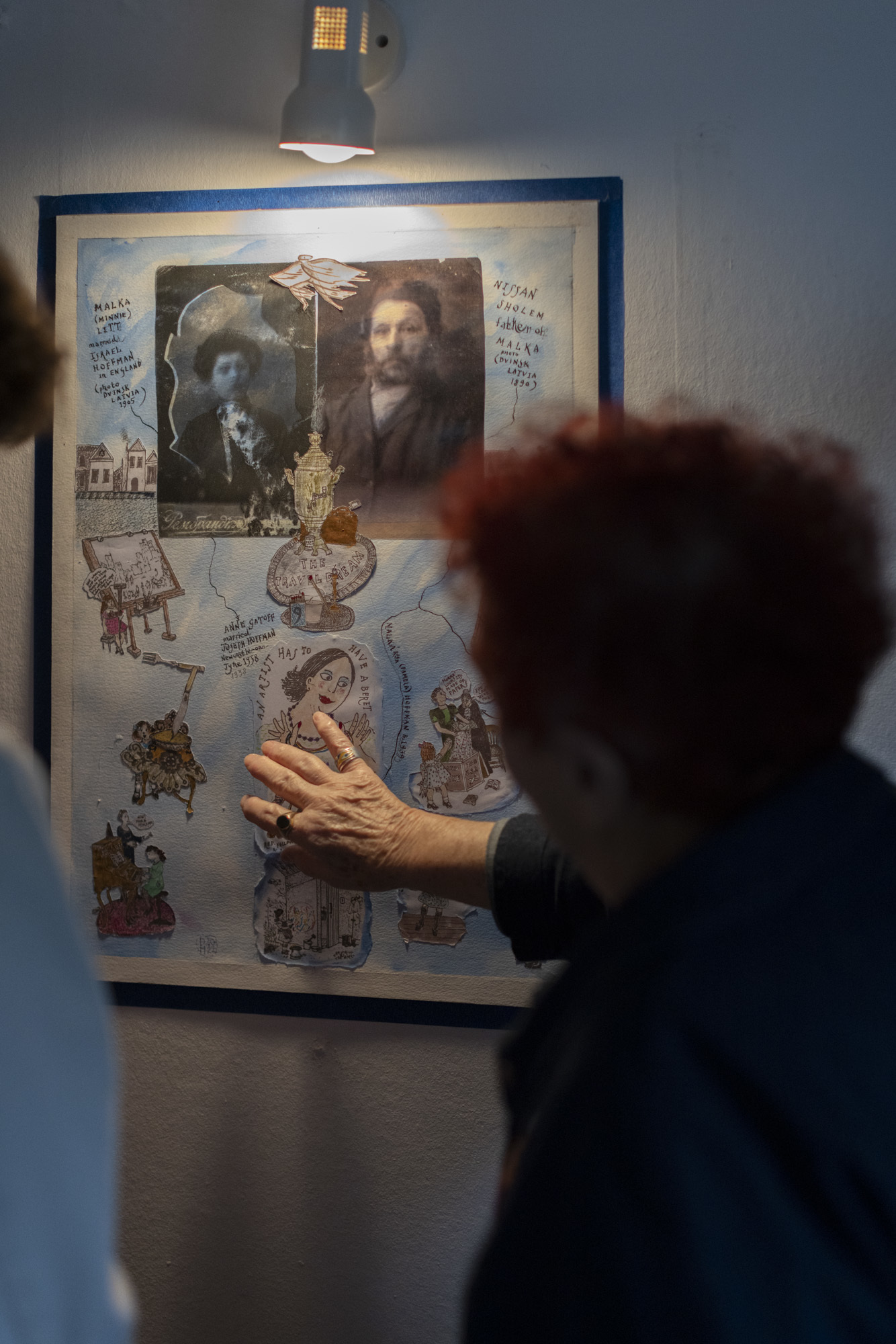 Pamela Howard pointing at framed drawing work on a wall.