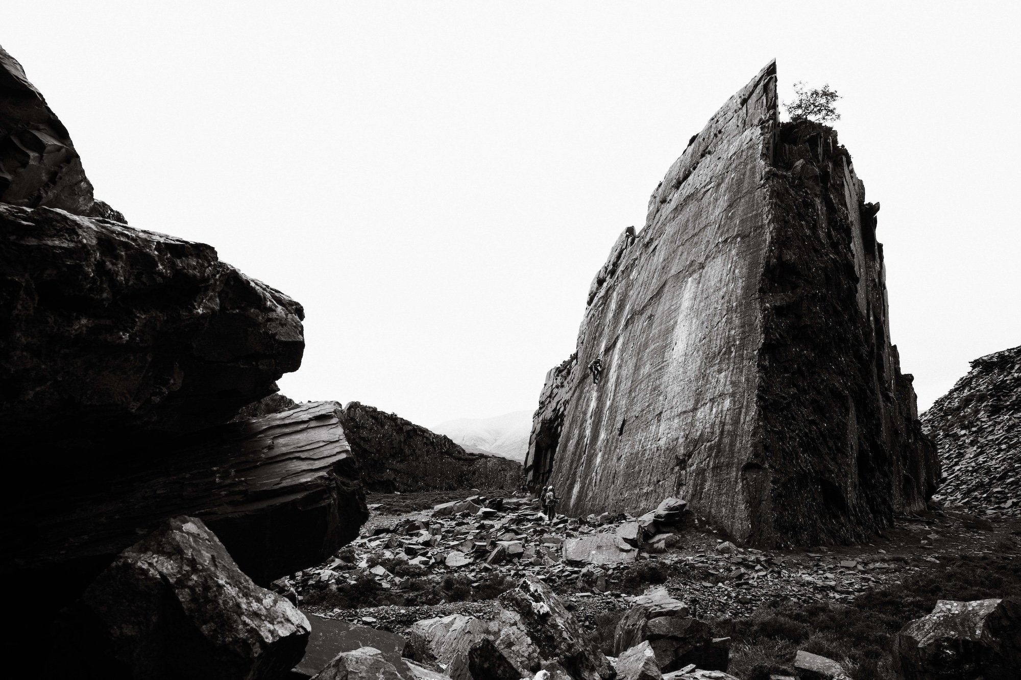 Black and white photo of two climbers looking up at a large rock.