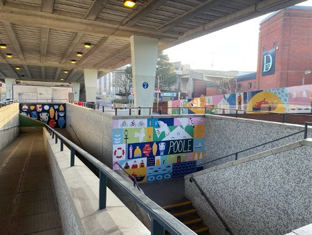 A set of walkways and cycling paths leading to and from an underpass. There are murals on the walls.