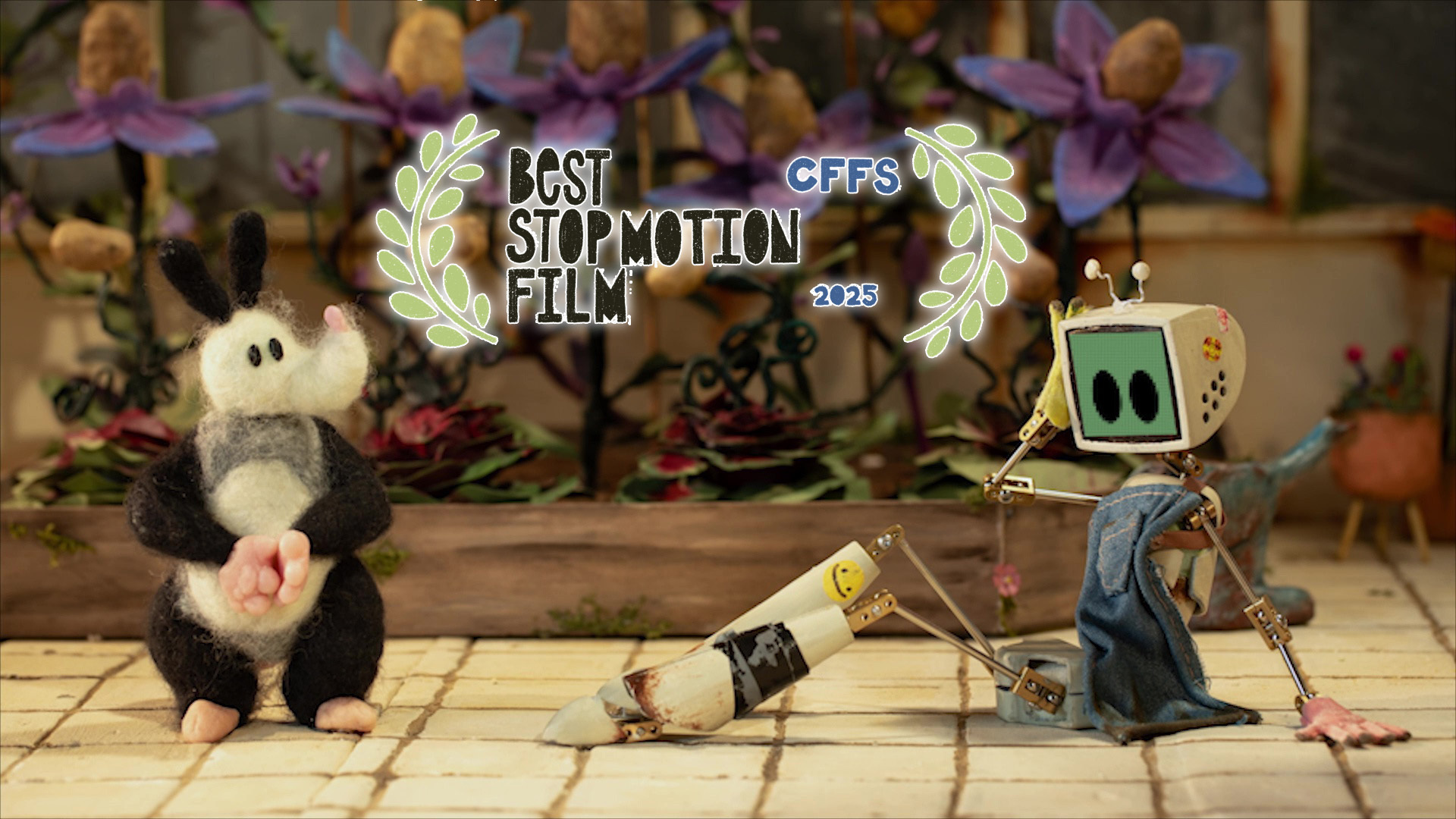 Stop-motion scene with white mouse character in black outfit and small robot with green screen face on tiled floor. Award laurels overlay.