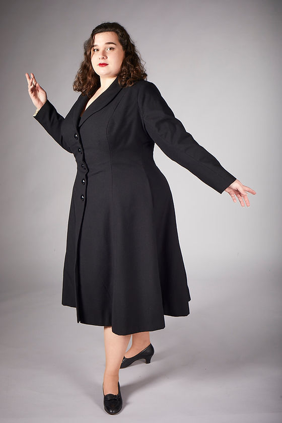 A model in a dark-coloured coat poses for a photo.
