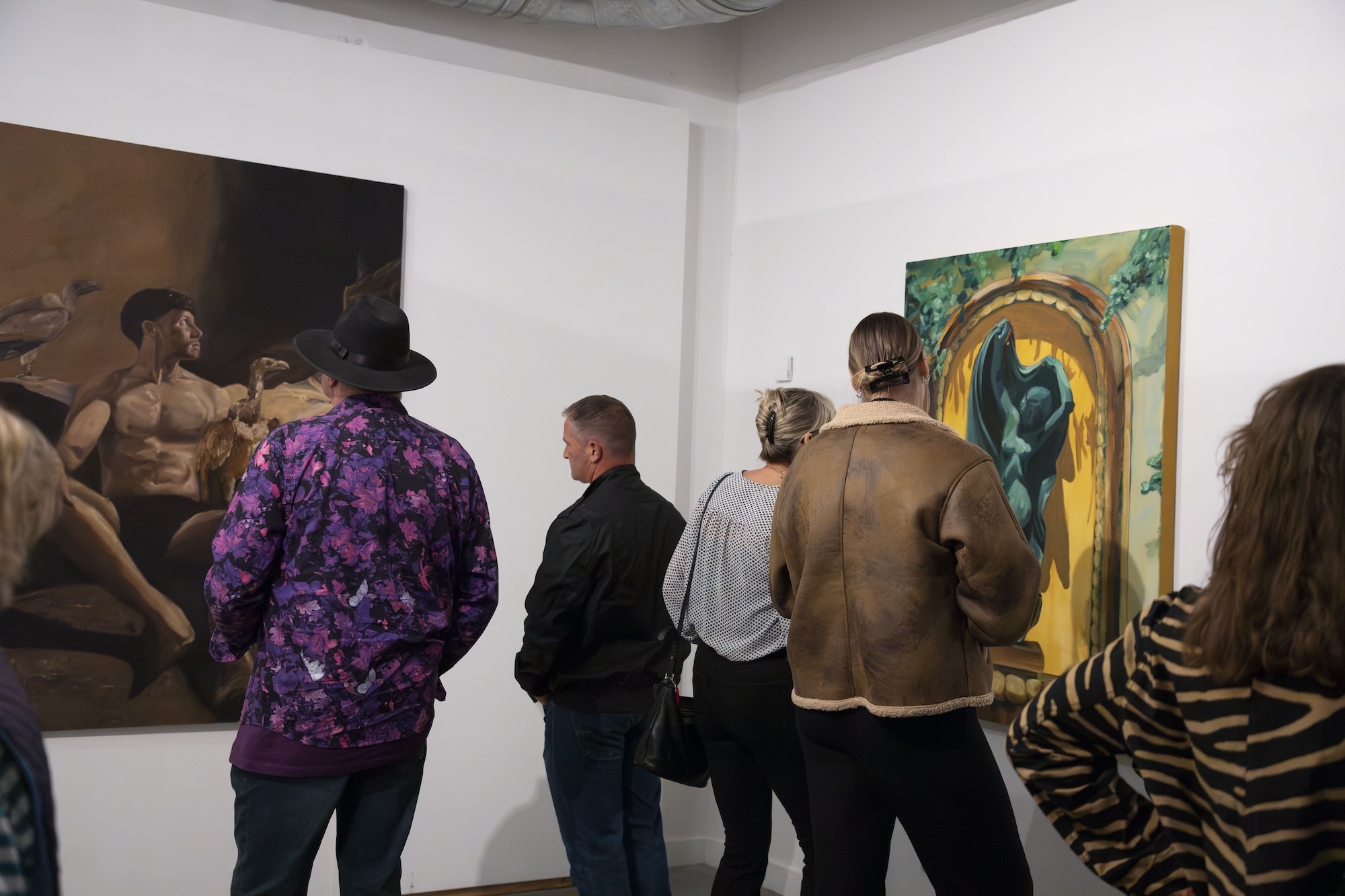 Members of the public viewed from the back, looking at two paintings on display during the MA Painting 2024 show at Poole Lighthouse.