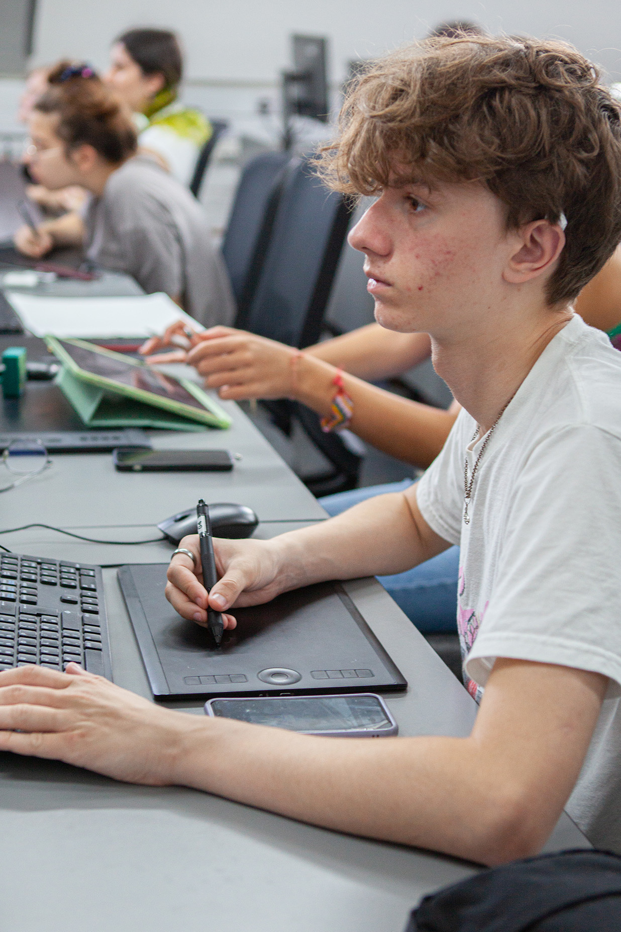 A student is using a table to draw a design on a computer