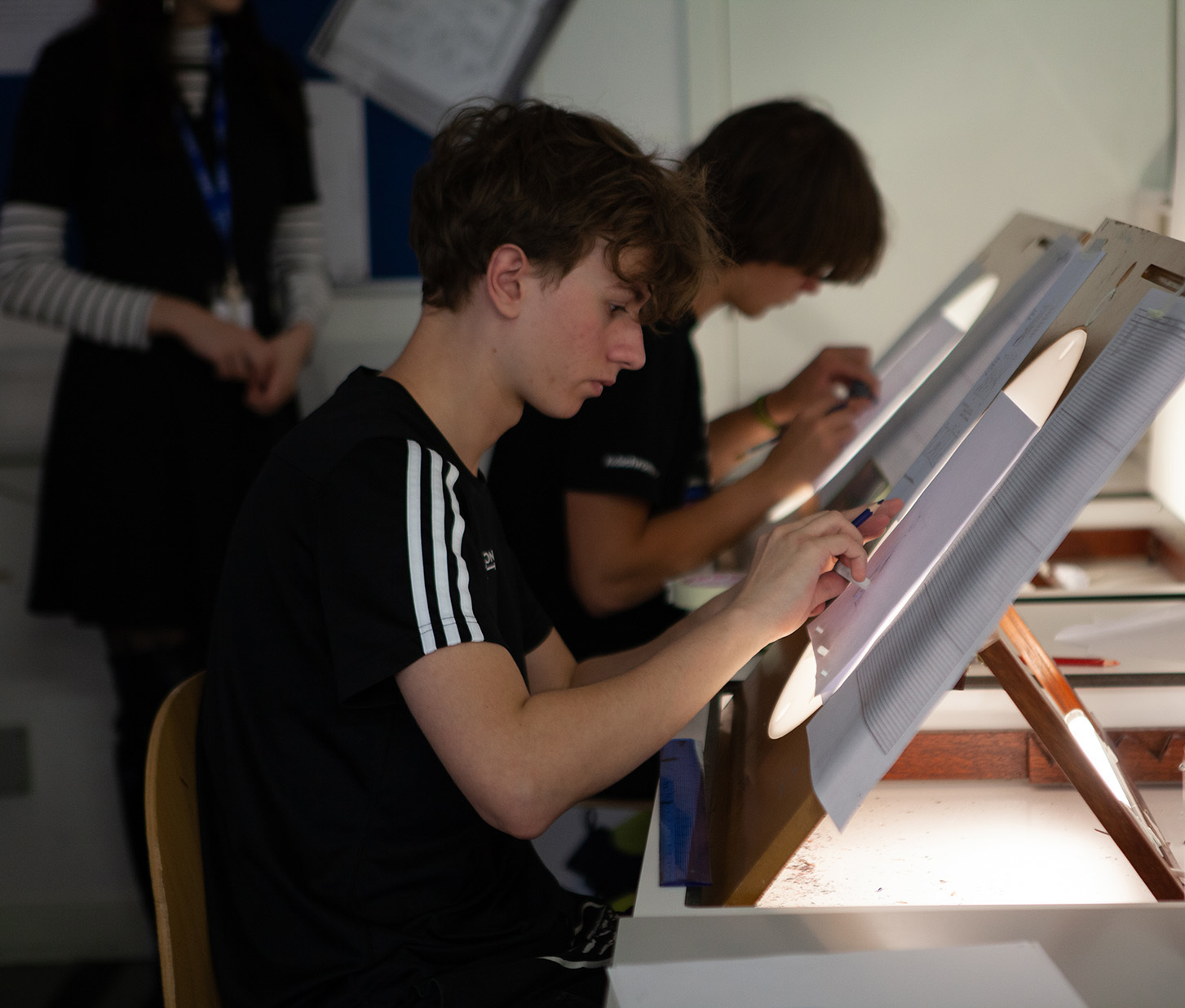 A student is drawing on a light box