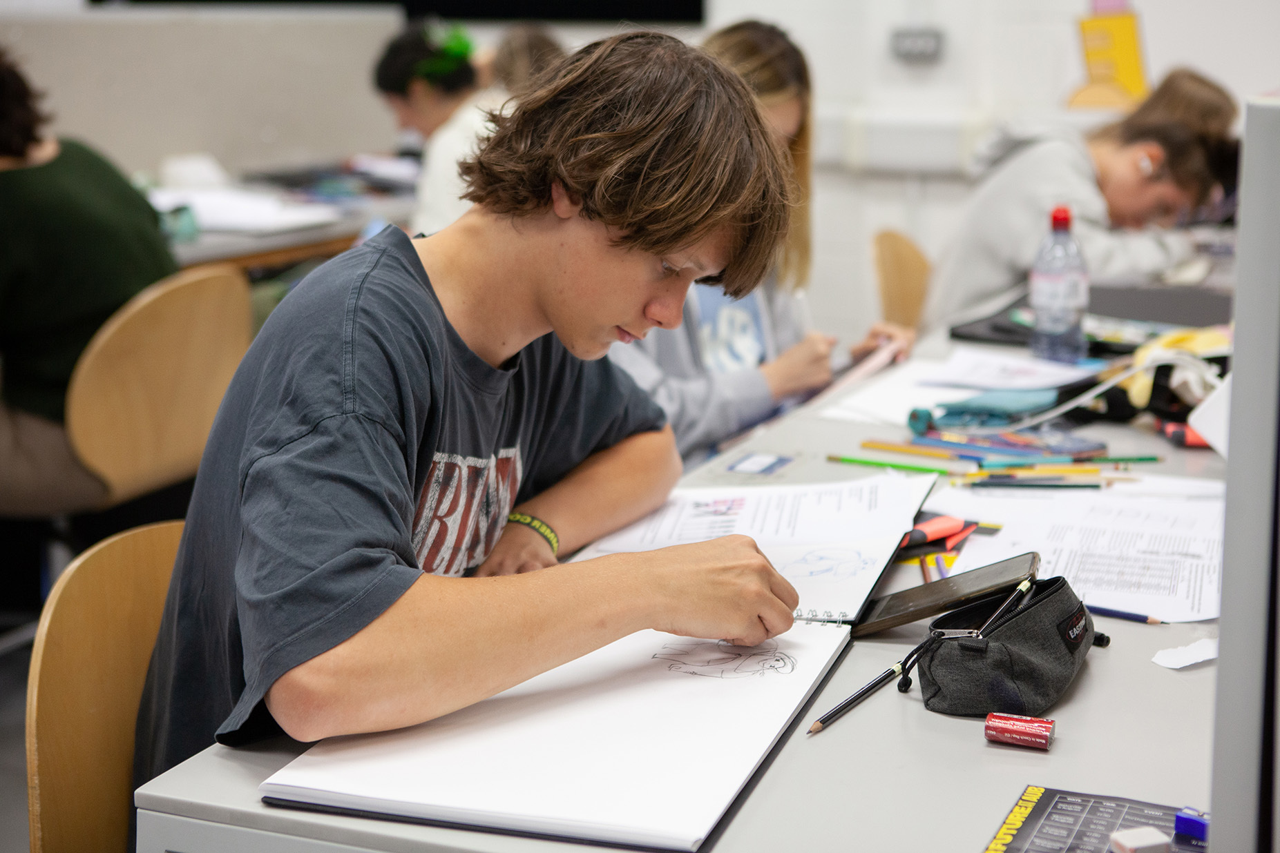 A student is drawing in a sketchbook
