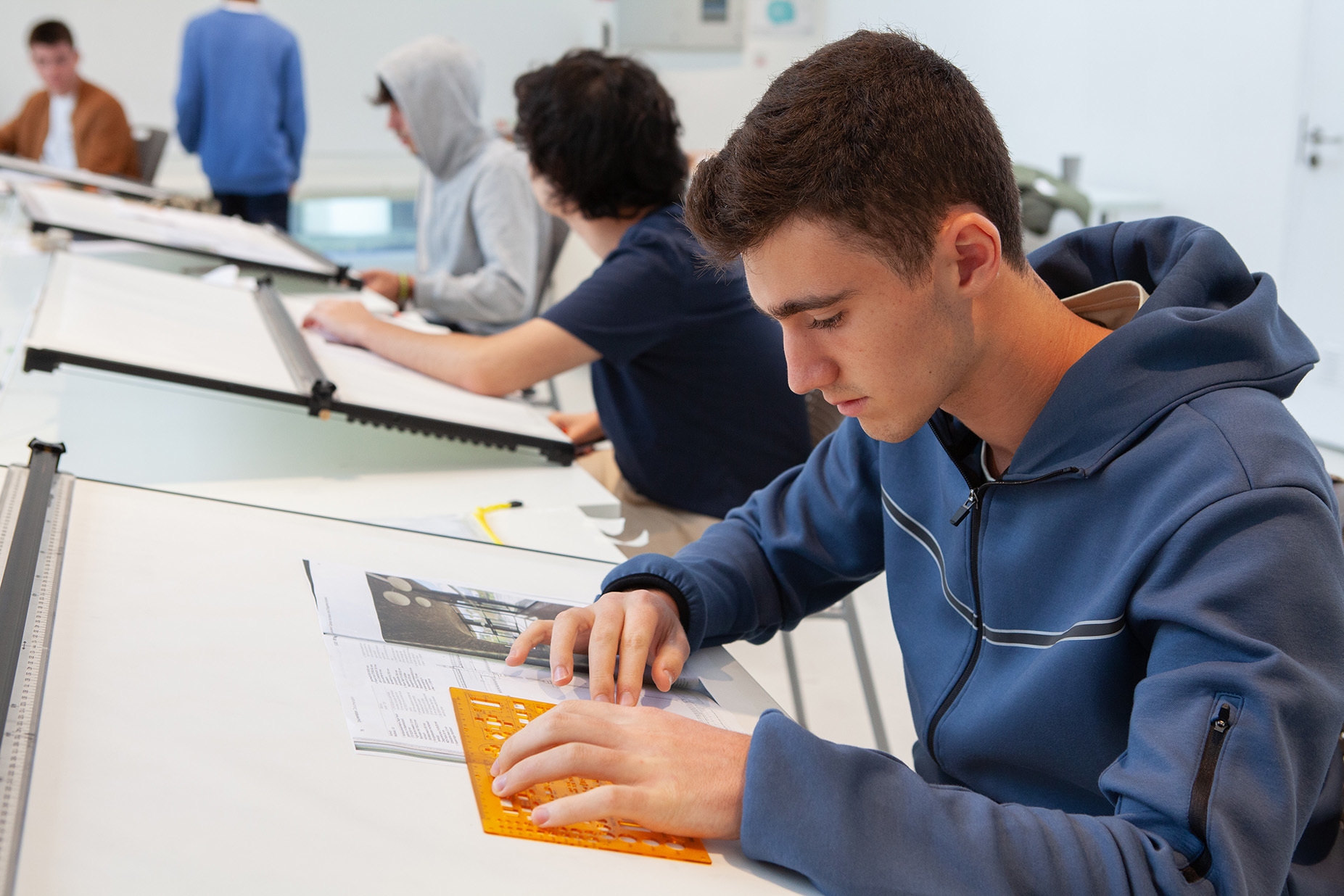 A student measuring scale of an architectural drawing in their sketchbooks