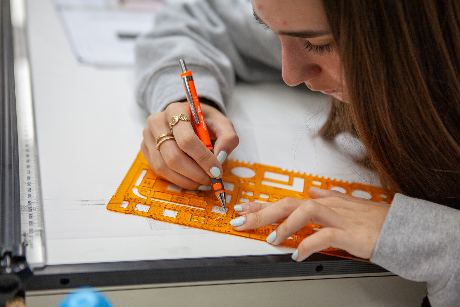 A student uses an architecture ruler to draw in their sketchbook