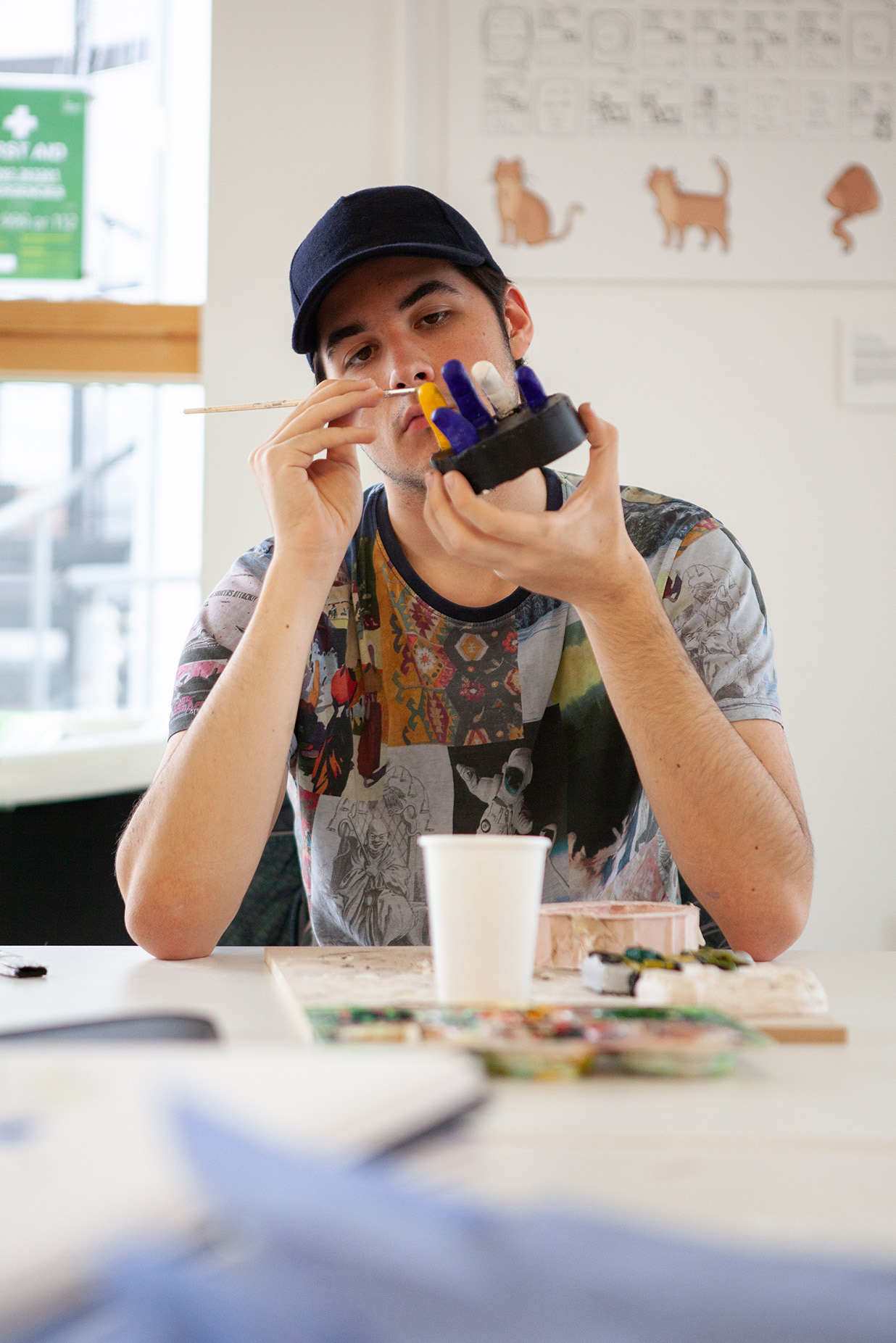 A student is holding a small sculpture and is painting it