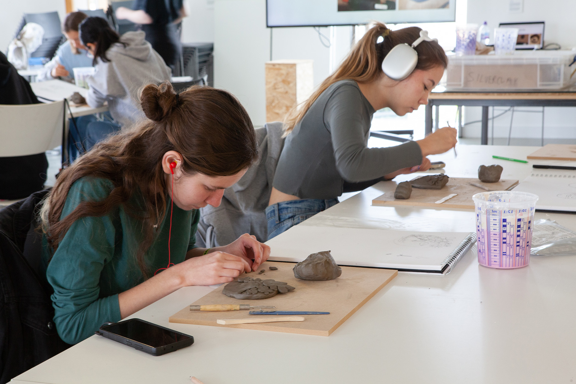 Two students are sat at a table crafting with clay