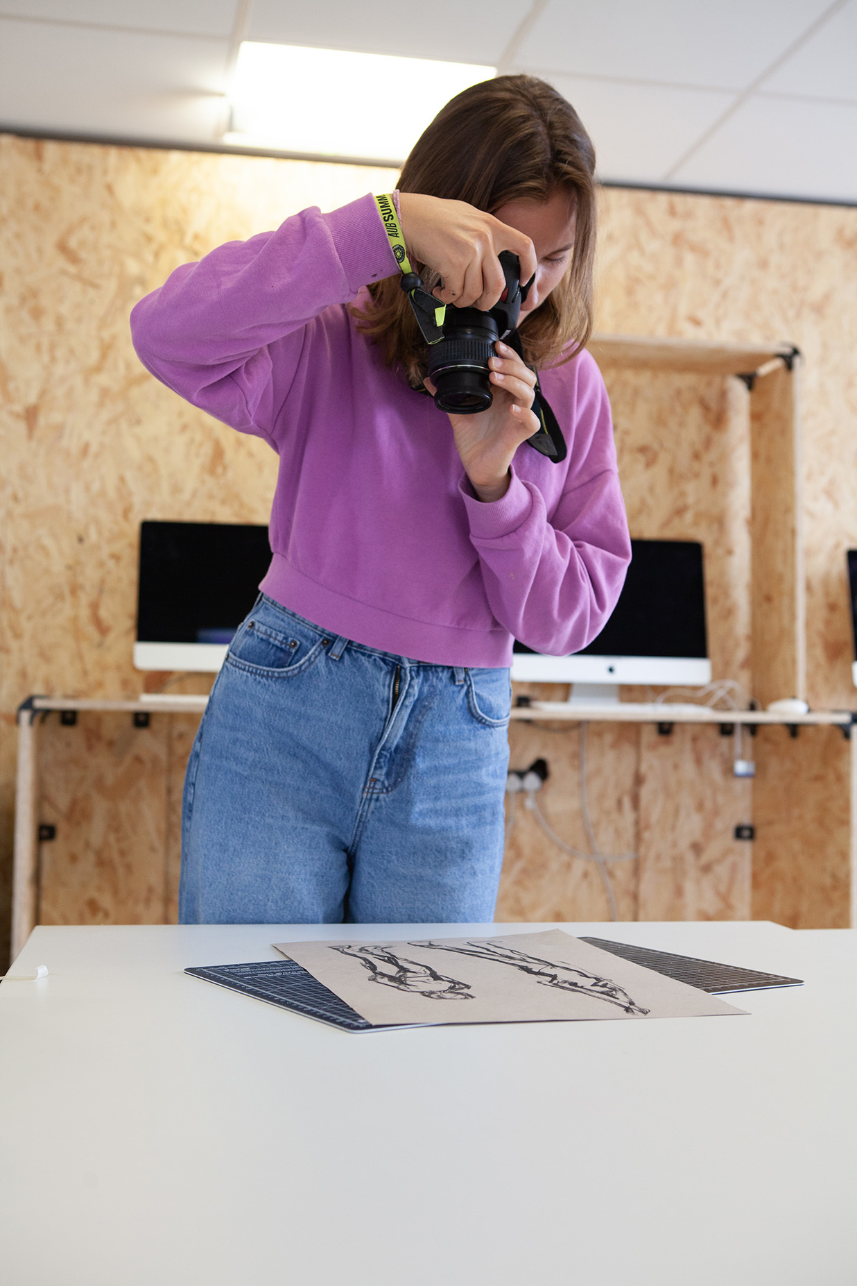 A student is taking a photo of a picture on a desk