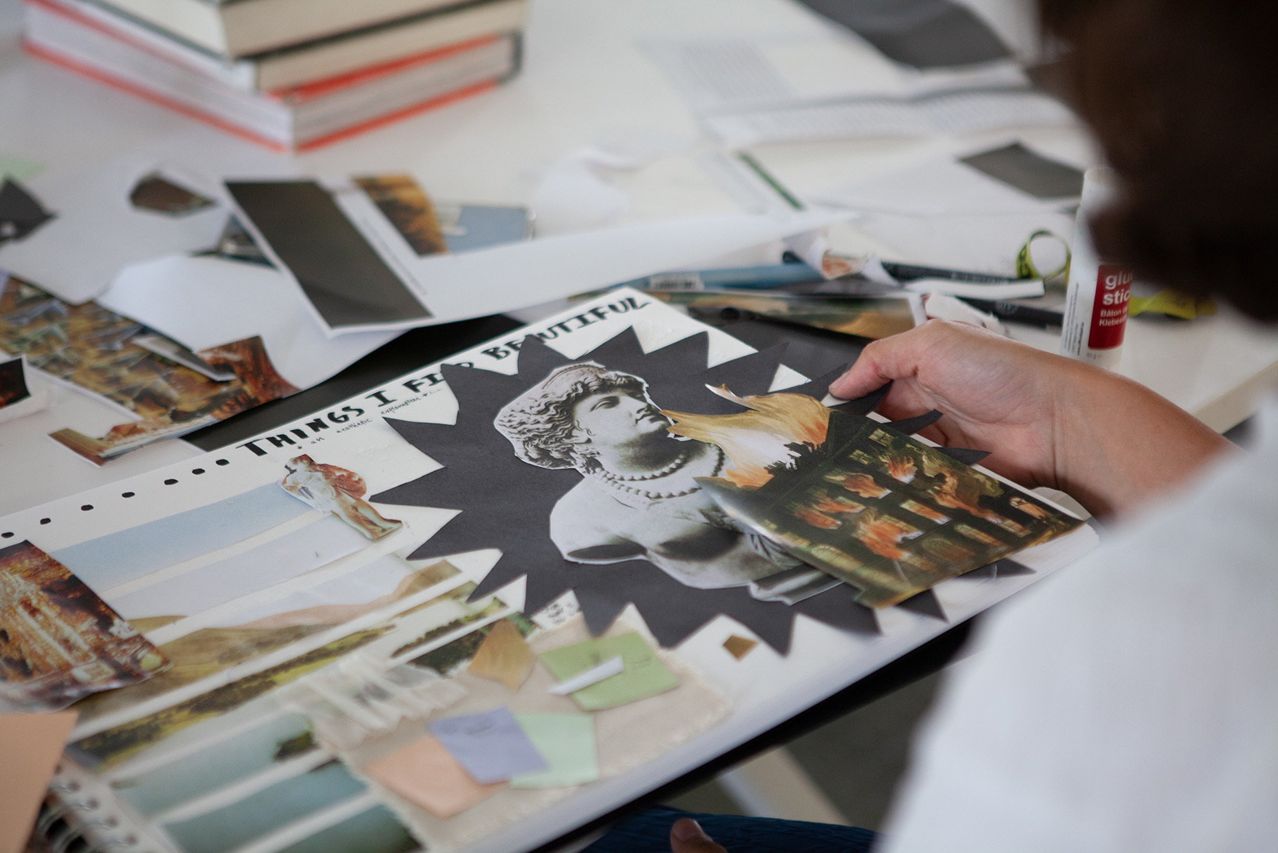 A student arranges collage pieces in a sketchbook