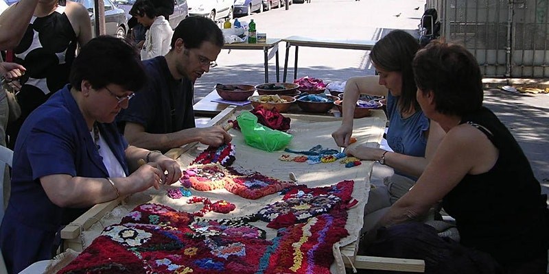 People sat around a long table working on a craft project.