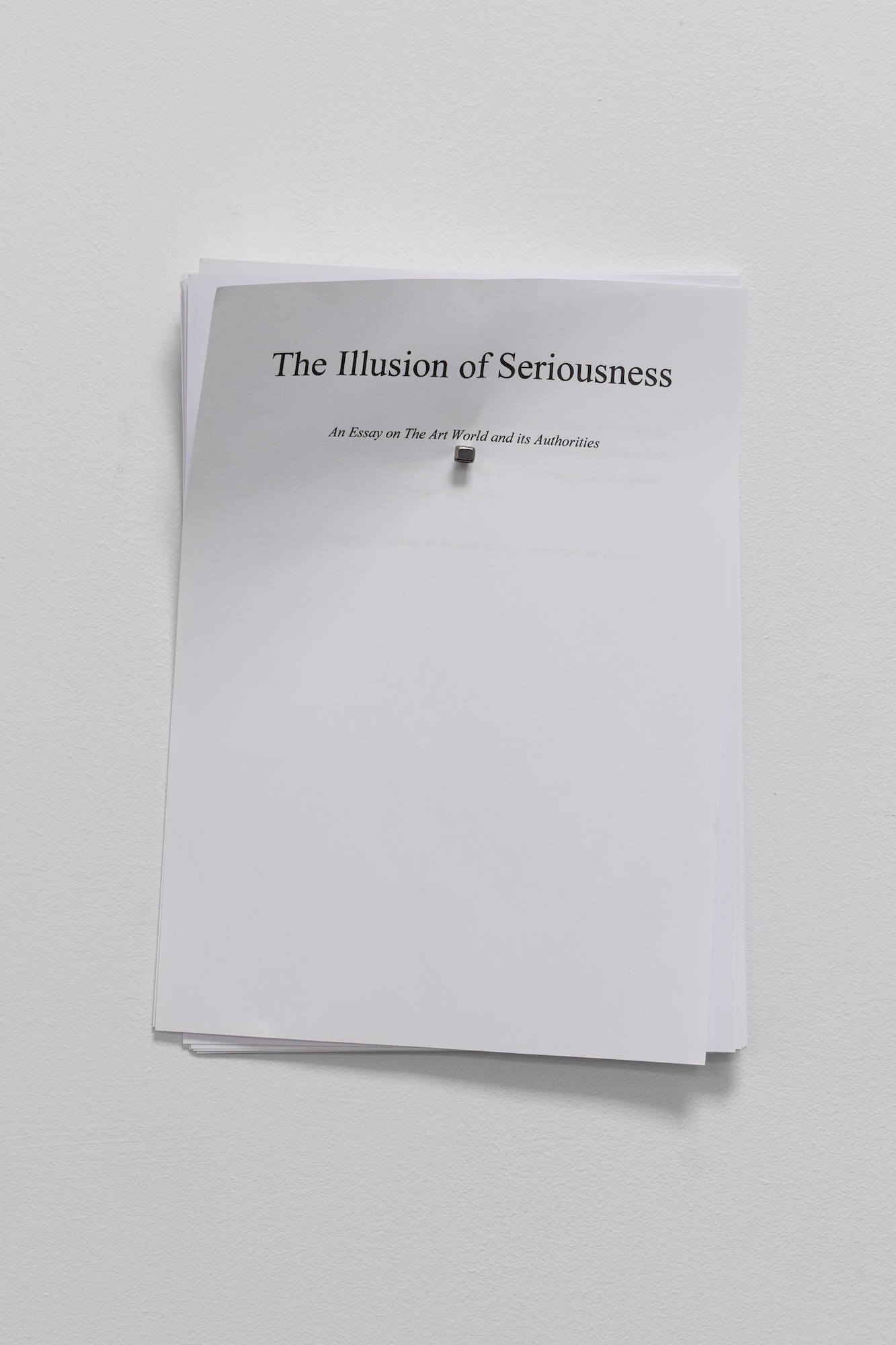 White book cover with black text reading "The Illusion of Seriousness" and subtitle, mounted on light grey wall with shadow.