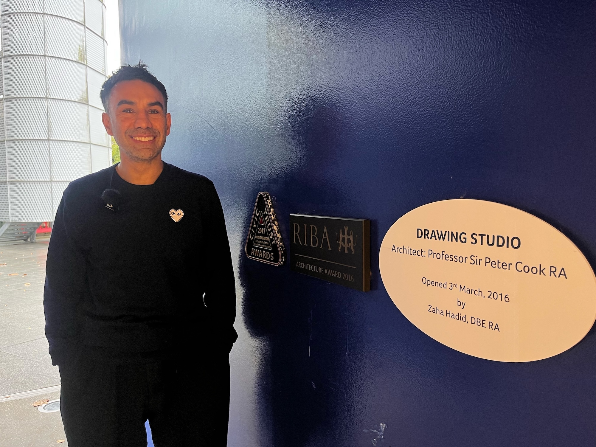 S Notghi standing in the doorway of the Drawing Studio at Arts University Bournemouth with oval brass nameplate reading "Drawing Studio Architect Professor Sir Peter Cook RA"