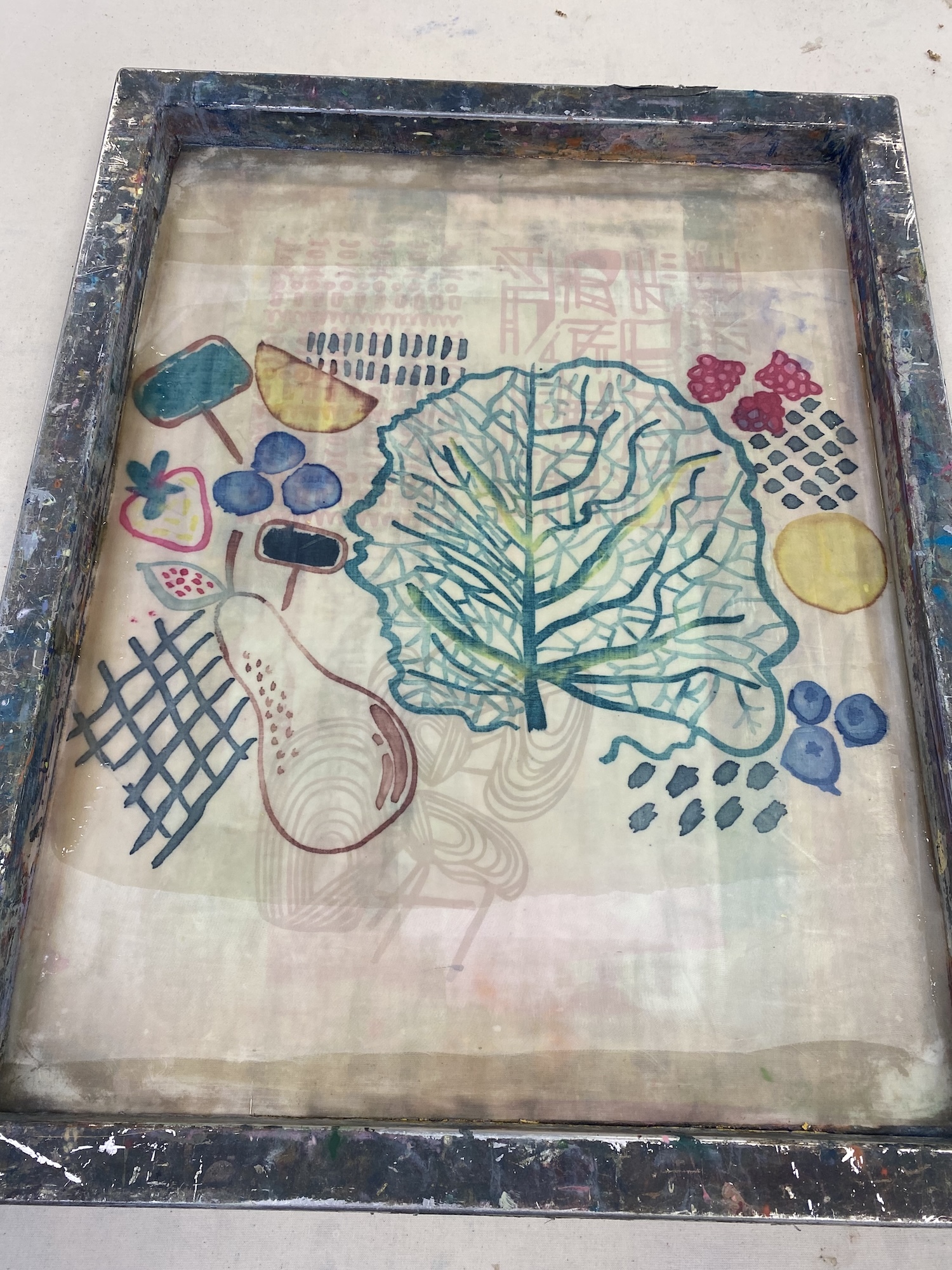 Artwork in procion printer with green cabbage leaf, blue circles, yellow shapes, red elements, and black grid patterns on cream background.