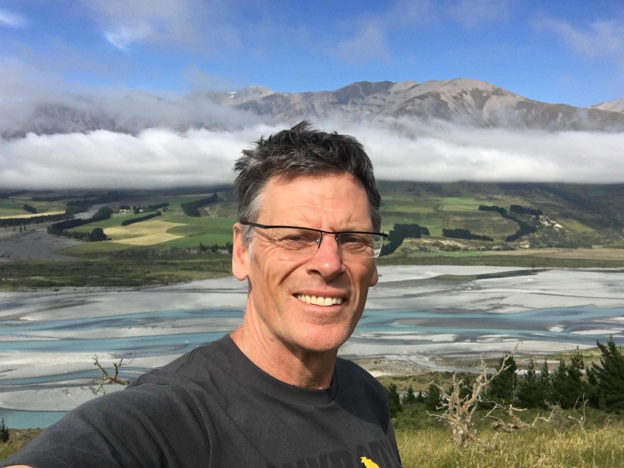 Headshot of P Gough with a New Zealand landscape in the background