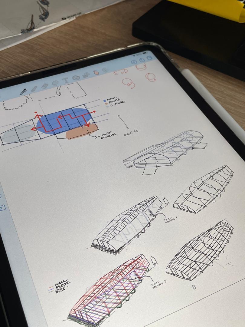 Tablet displaying architectural sketches with wireframe building designs, including blue and orange coloured sections and geometric line drawings.