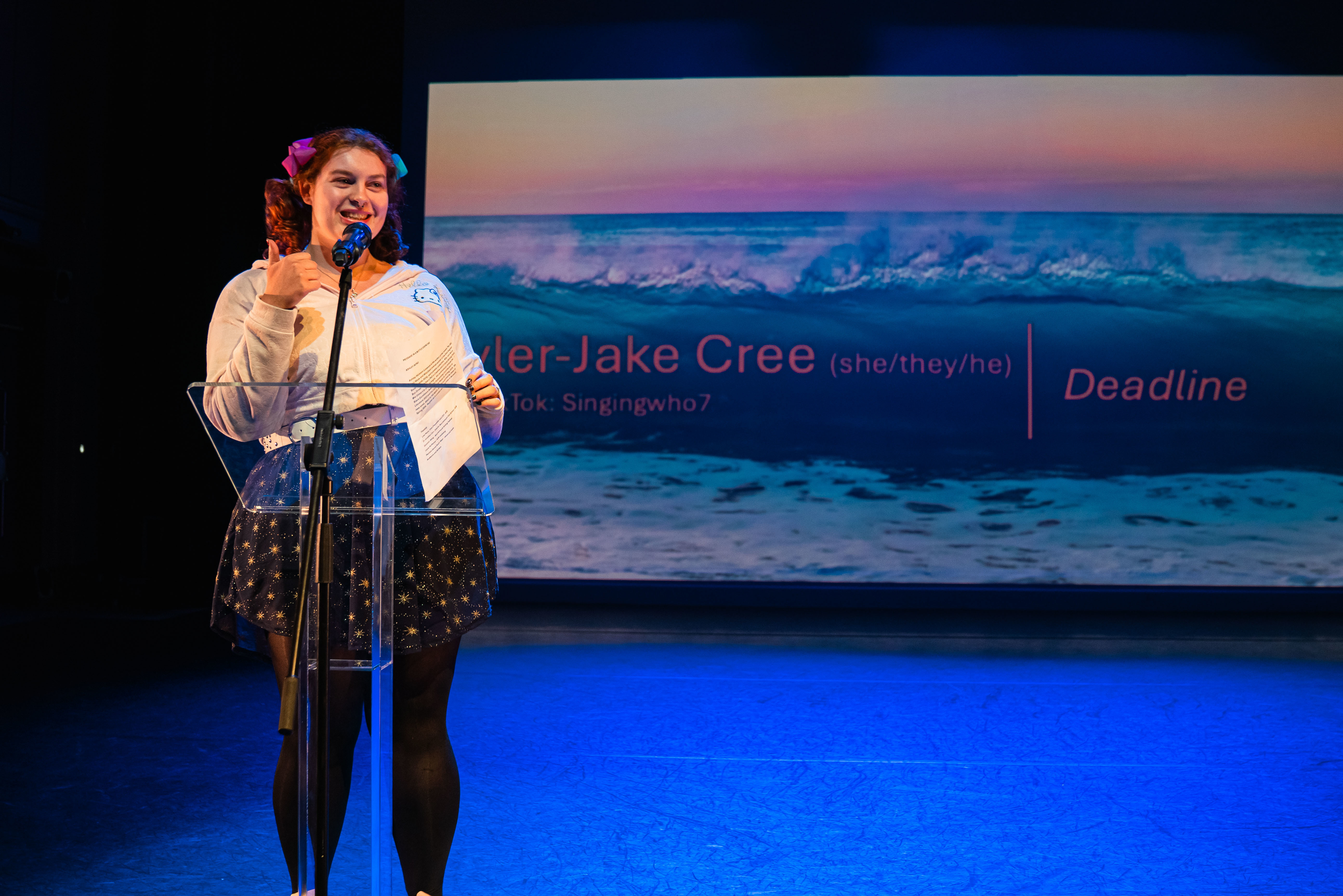 An AUB BA (Hons) Creative Writing student standing at a lectern performing for an audience off-camera at Bournemouth Writing Festival.