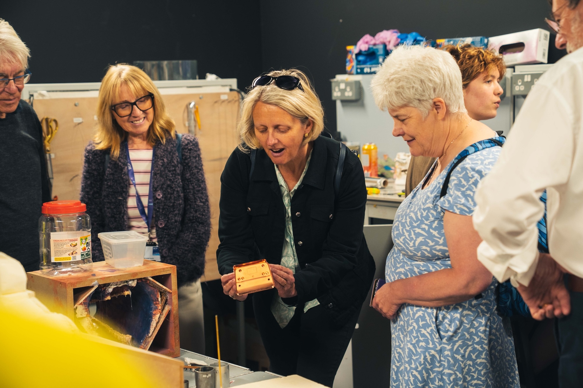 A small group of Bournemouth, Poole and Christchurch councillors visiting Elliott Road Studios. One of the councillors is handling a small metal object while the others watch.