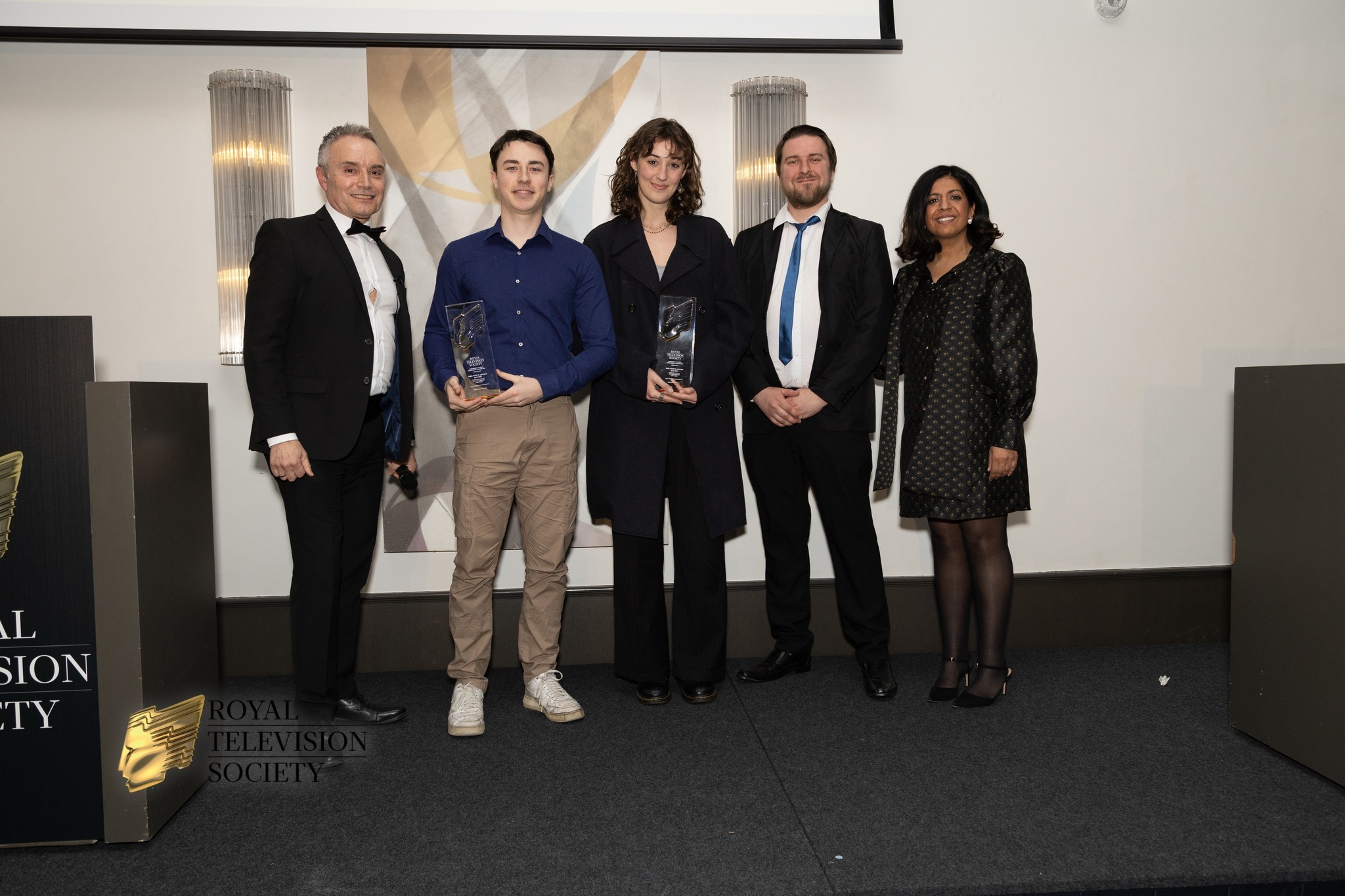 BA (Hons) Animation Production graduates N Busschaert and V Draghi standing with officials and posing for a photo at the Royal Television Society Southern Awards.