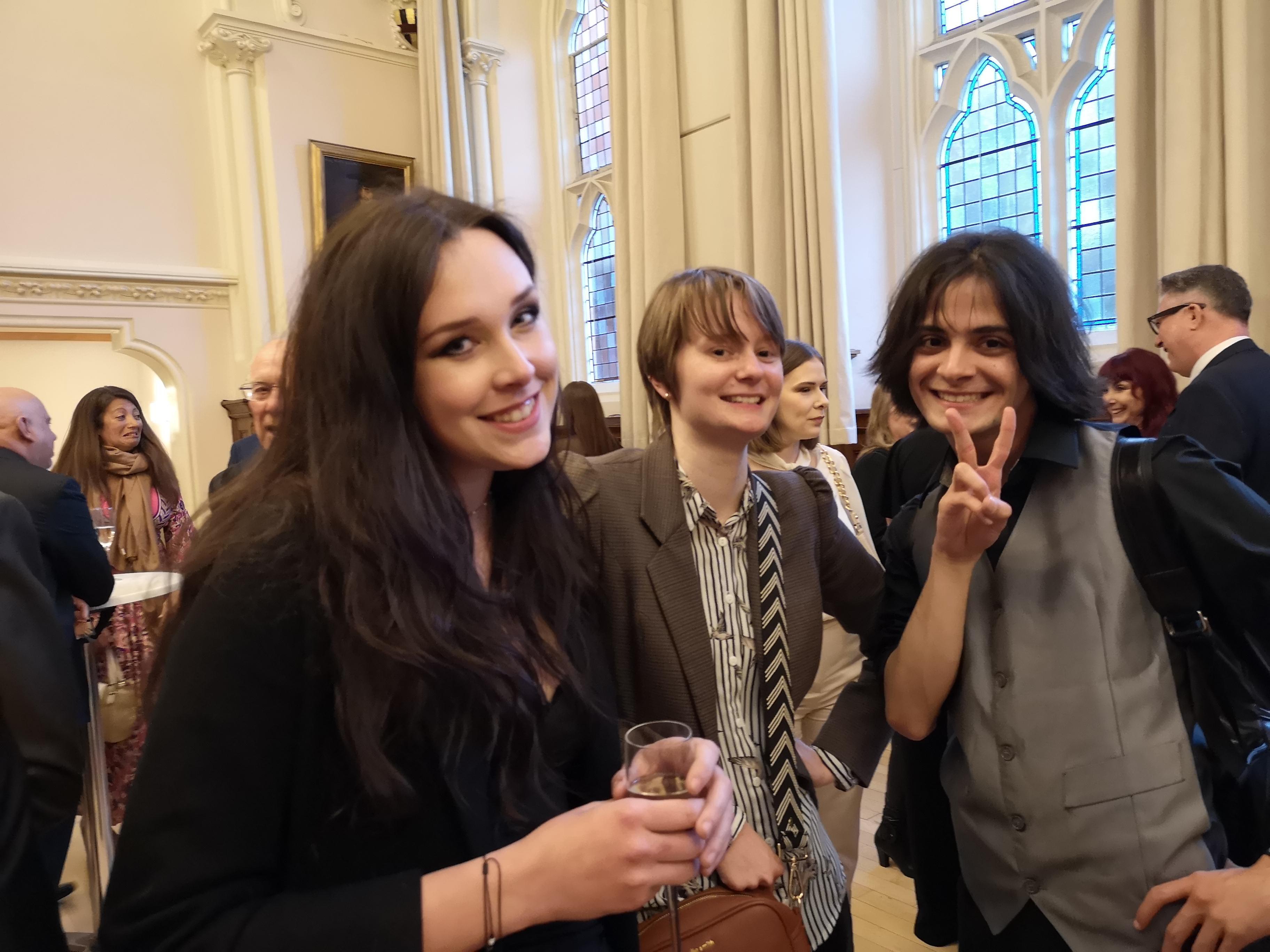 Three people stand and pose for a photo at an event.
