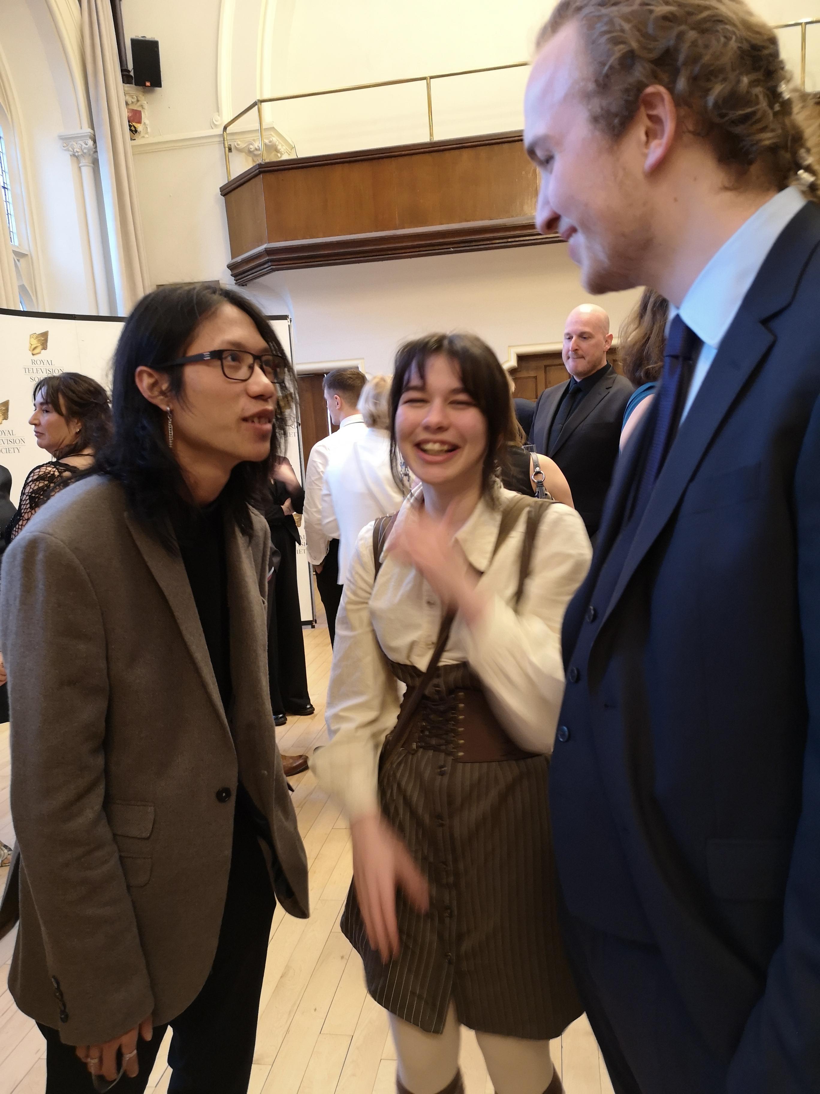 Three people talking and laughing at an event.