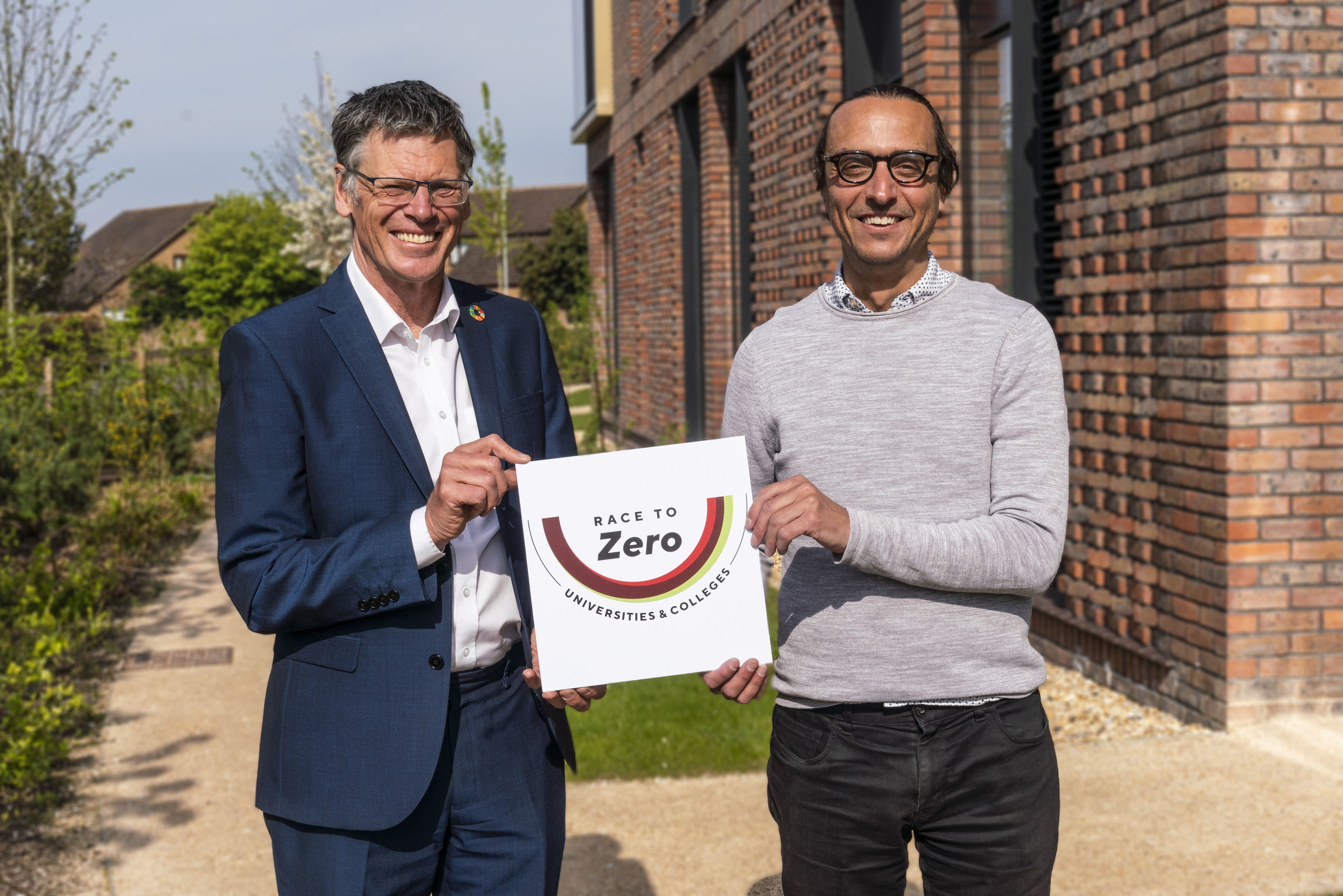 Professor Paul Gough and James Jackson holding up a plaque with text reading: 'Race to Zero Universities and Colleges'.