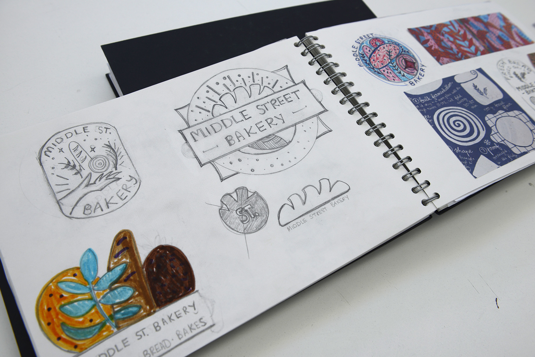 Sketchbook open with a few pencil designs for the Middle Street Bakery logo.