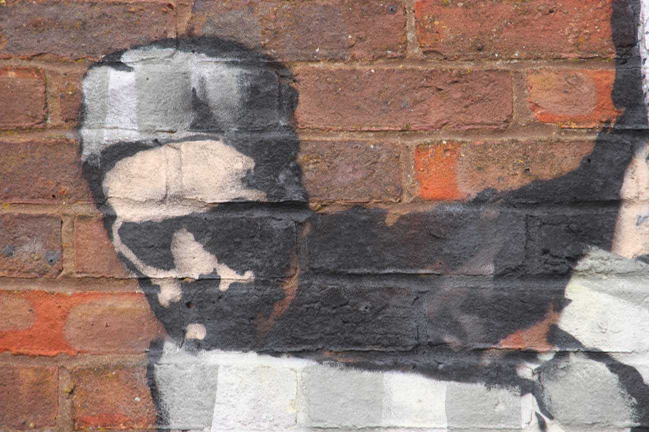 Close-up of a piece of Banksy artwork on a brick wall.