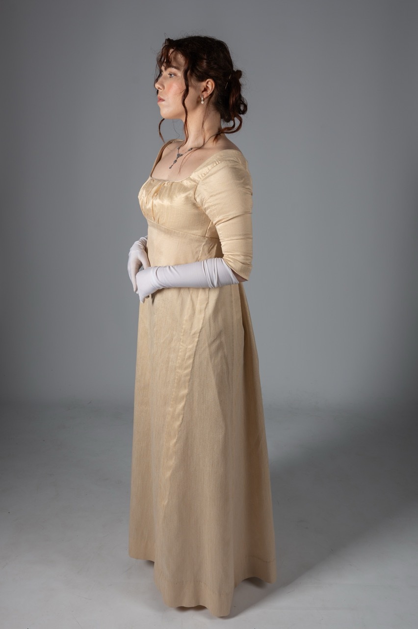 Woman in profile wearing cream-coloured Regency-era gown with empire waistline, long white gloves, hair in updo with ribbons.