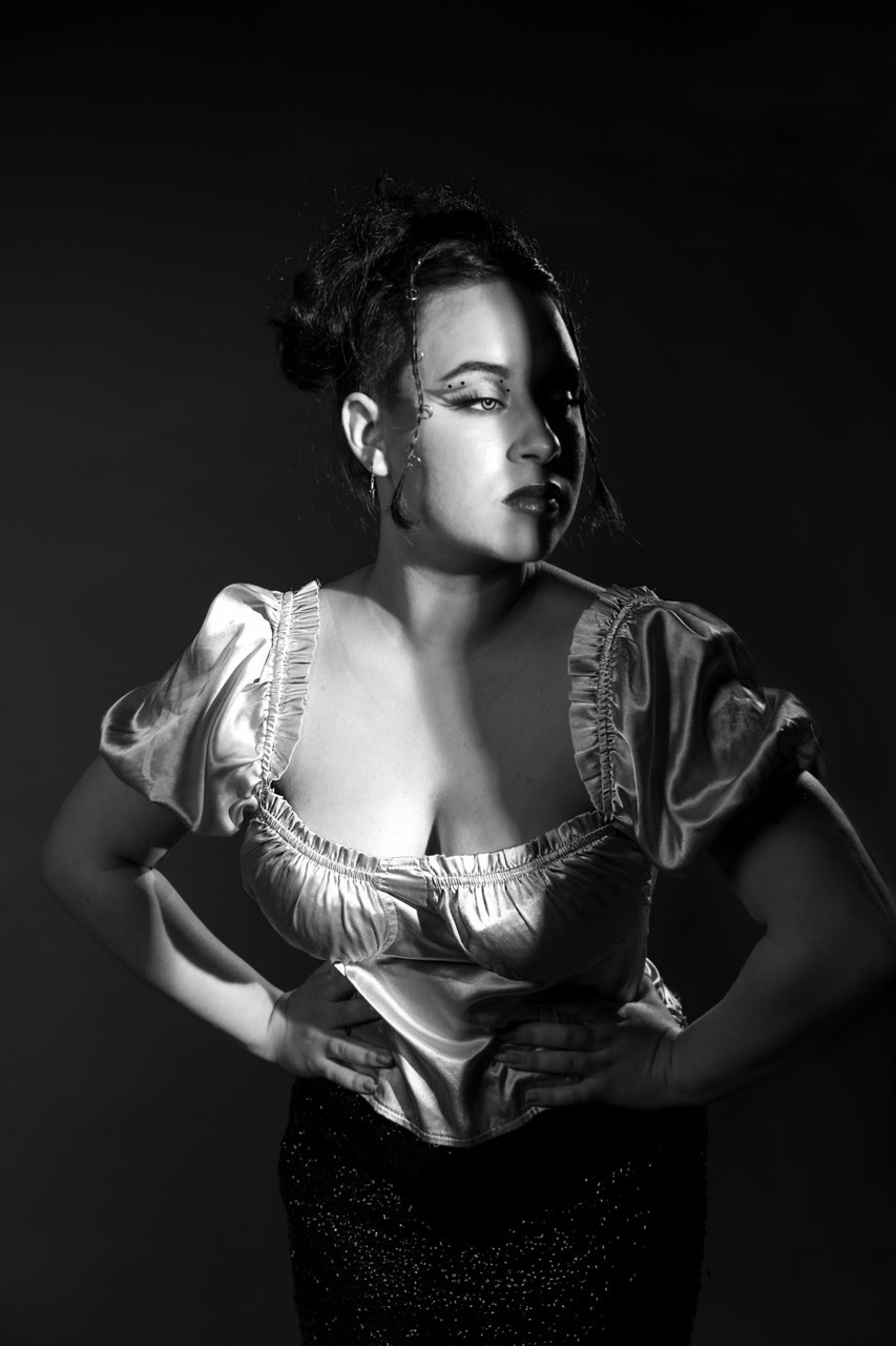 Kasandra Georgi posing half in light, black and white shot.