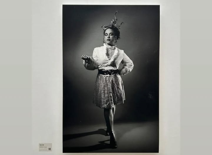 Kasandra Georgi posing in a black and white photo, showcased on a white gallery wall.