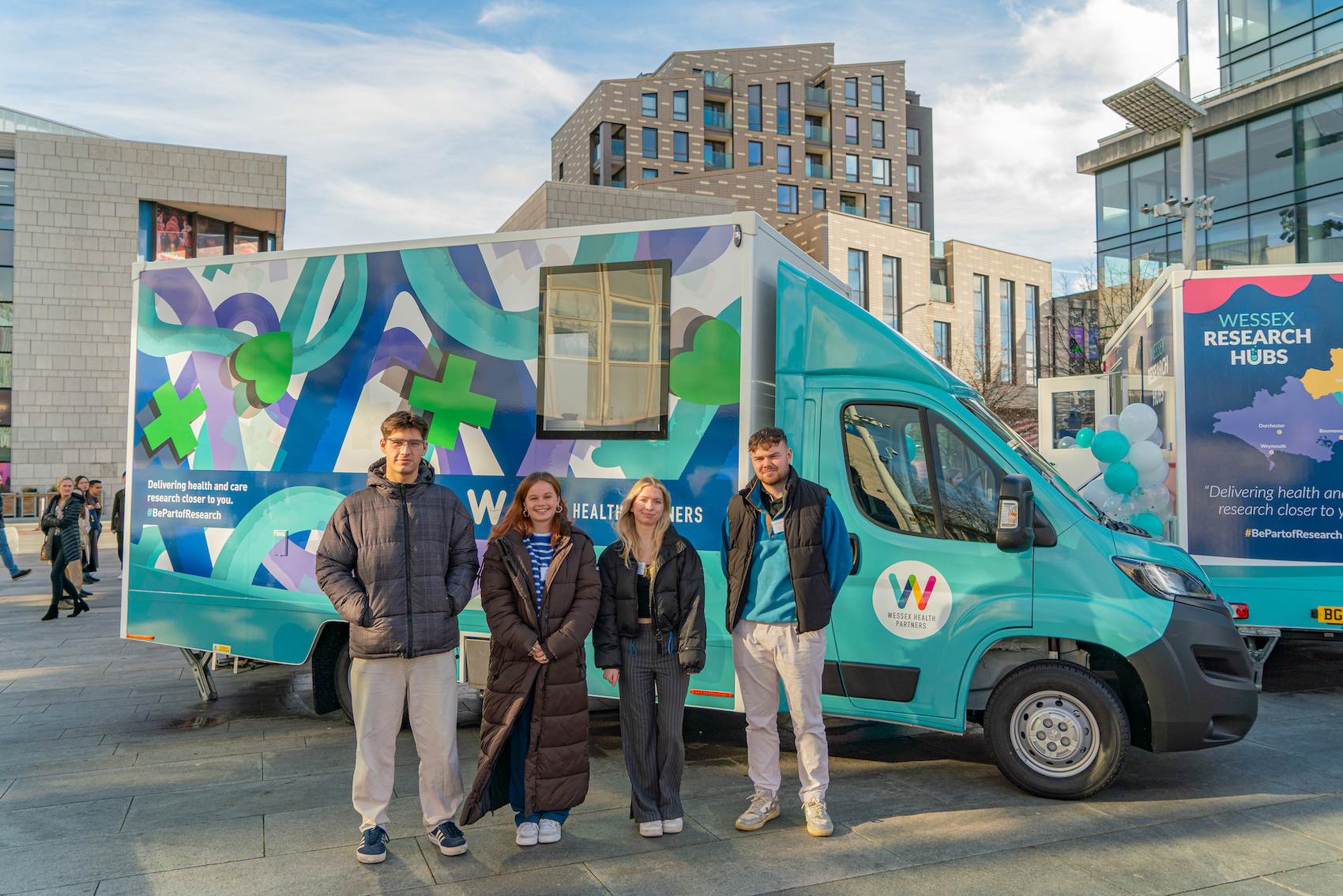 Four BA (Hons) Interior Architecture and Design students pose for a photo in front of an NHS/NIHR Research Bus in Southampton.