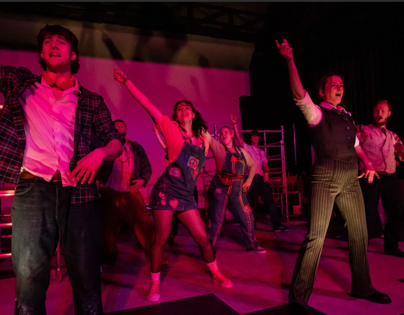 A group of BA (Hons) Acting students pose as they perform a dance routine under dim pink lighting.