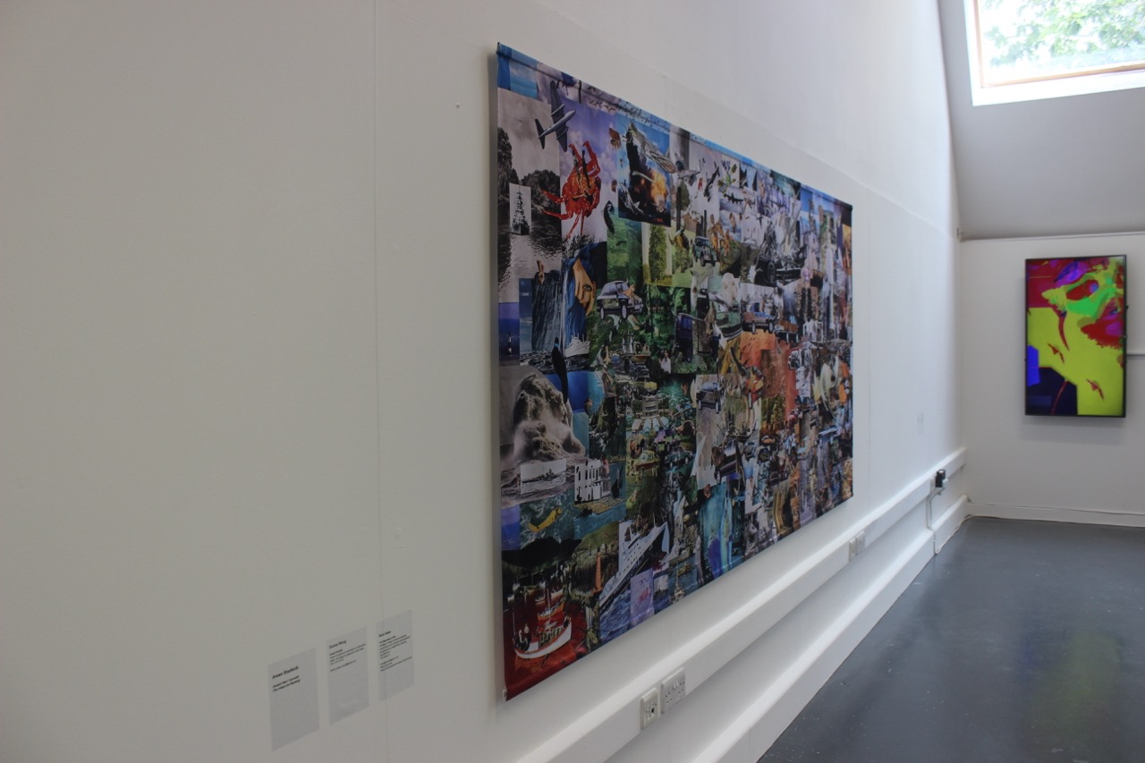 A large collage artwork displayed on a white wall, featuring a vibrant mix of images and textures. To the left are several small white information plaques, and to the right is a bright, abstract painting in a contrasting frame.
