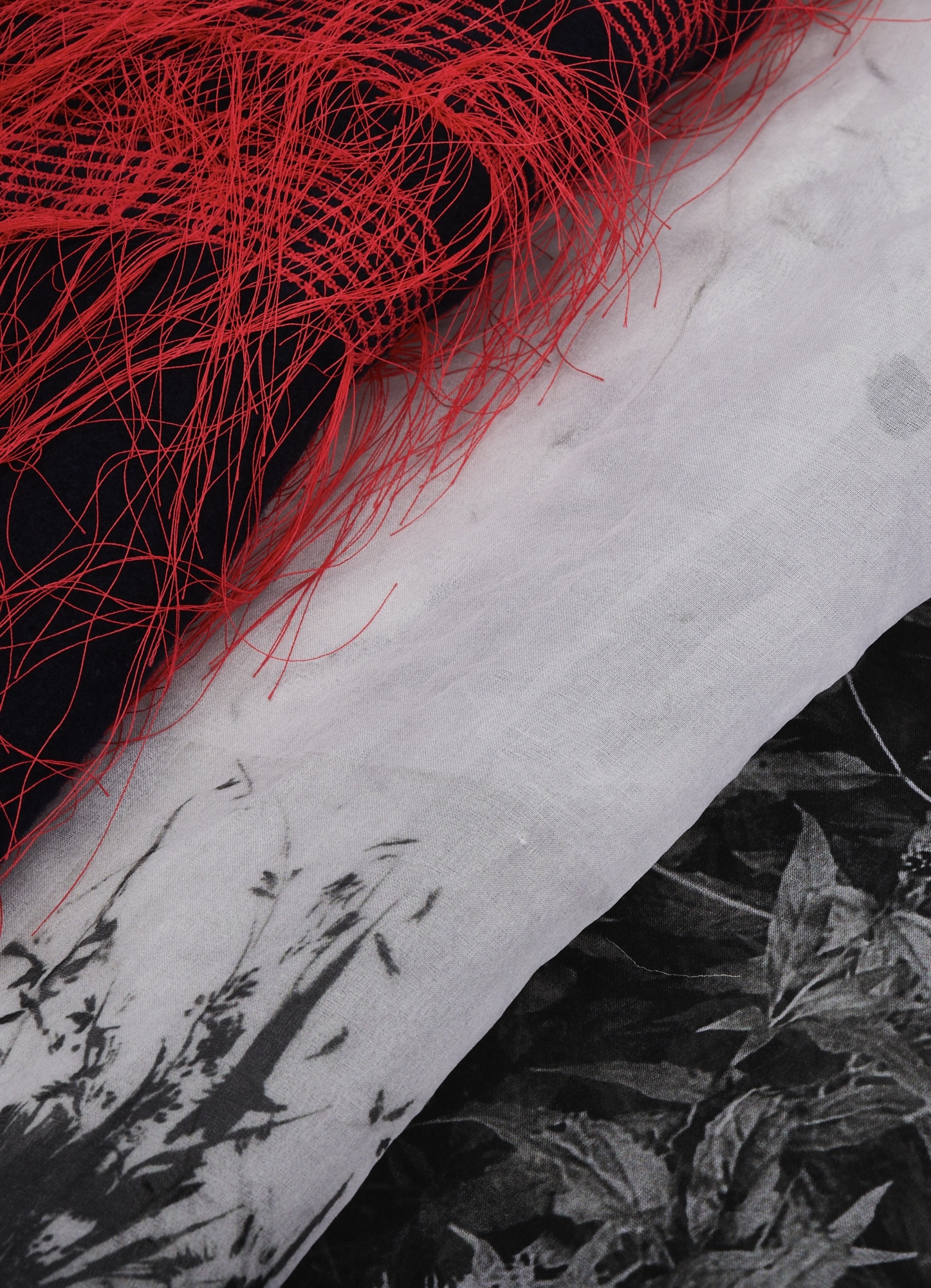 Rolls of black and white fabric (some with red feather trimming) with a plant/floral pattern.