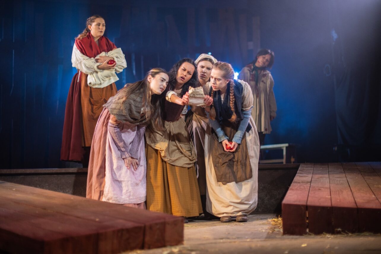 The Ballad of Maria Marten – AUB actors on stage in costume with wood panels and blue lighting.