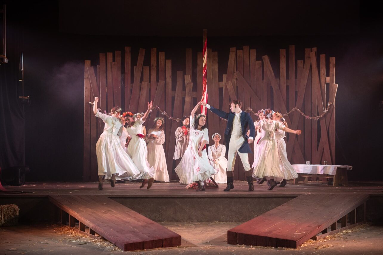 The Ballad of Maria Marten – AUB actors on stage in white dresses dancing with wood panelling.