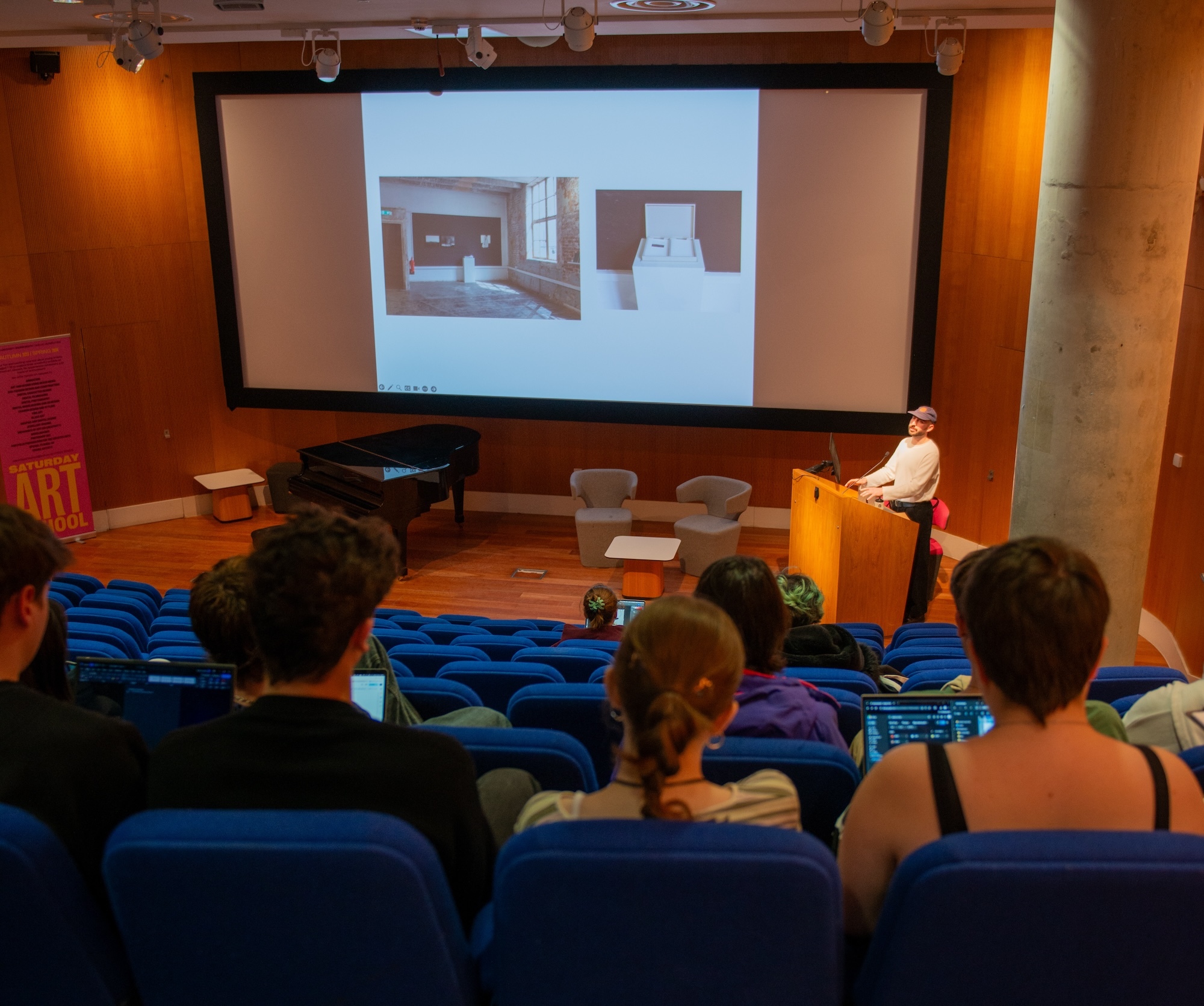 Photographer S P Cashmore giving a lecture in a lecture theatre to a group of students, sitting in seats in the foreground.
