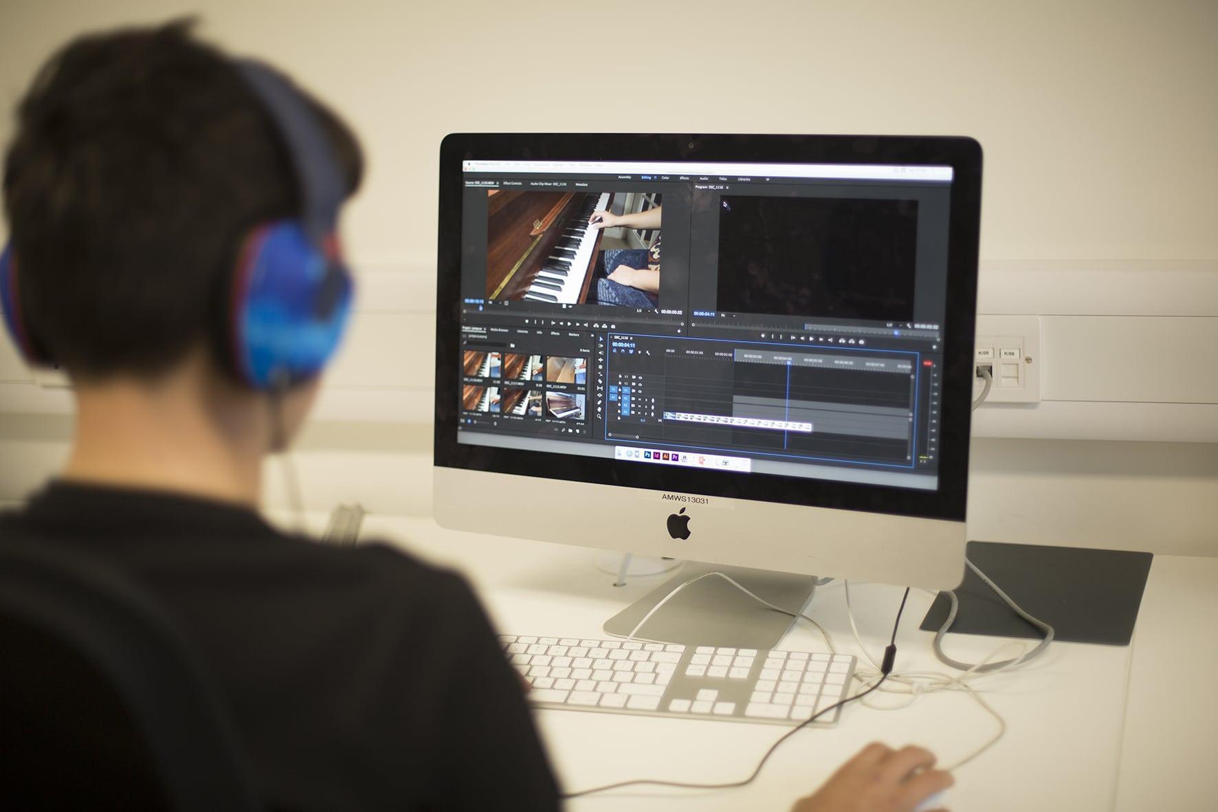 A person sits at a computer using editing software to edit a film. Film still shows a person playing a piano.
