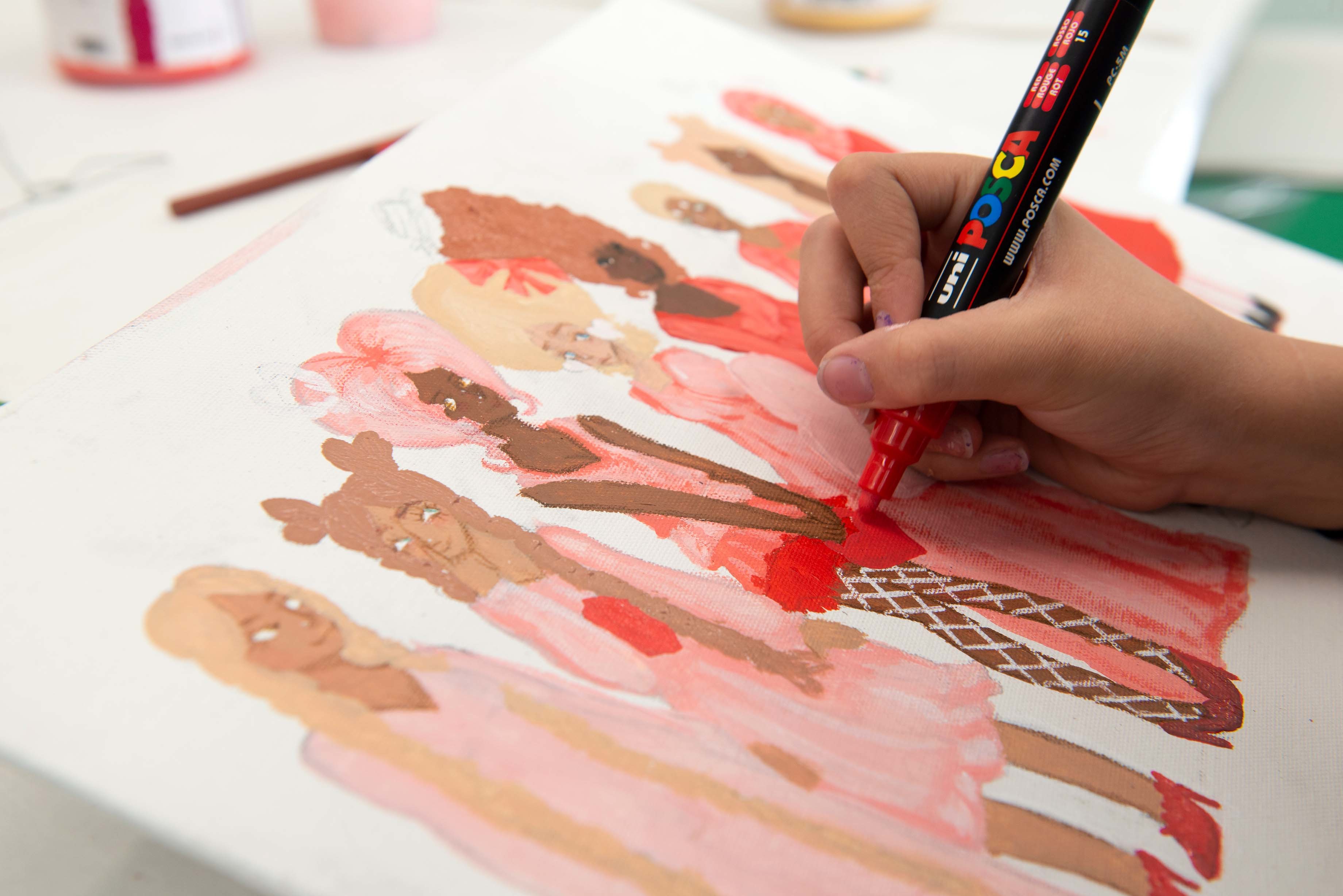 A person in the middle of colouring a drawing of a series of people lined up in different outfits.