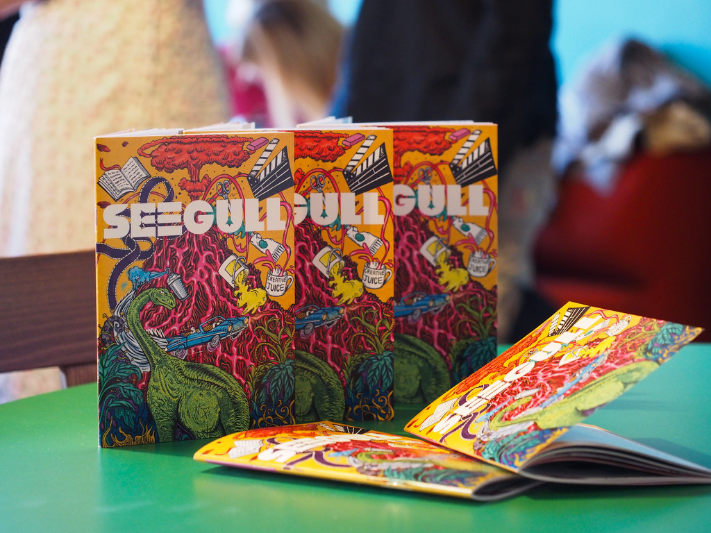 Three Yu-Gi-Oh! booster packs with orange and red dragon artwork standing upright on green table beside open cards.