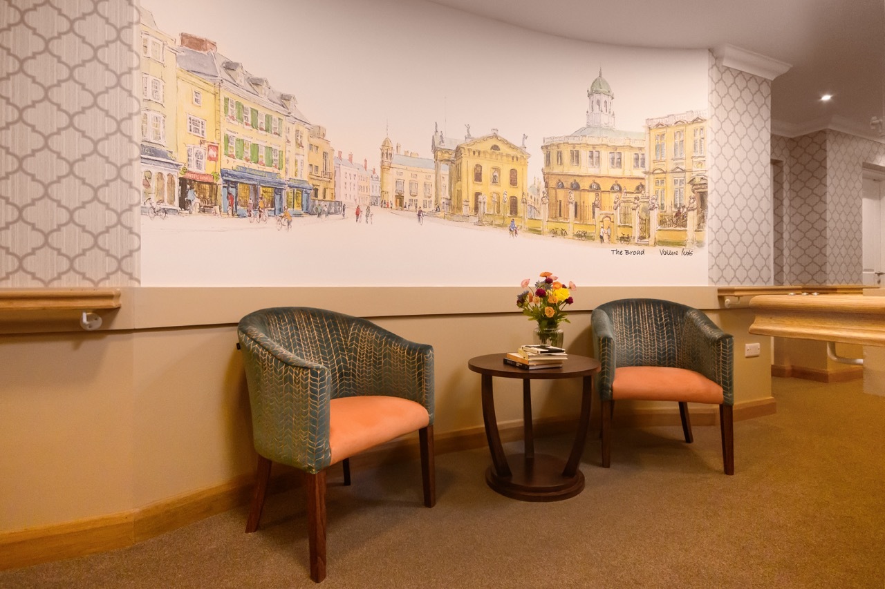 SF corridor in Diana Celella's 'Wellford Gardens Care Home' with two chairs and a large, architectural painting mural.