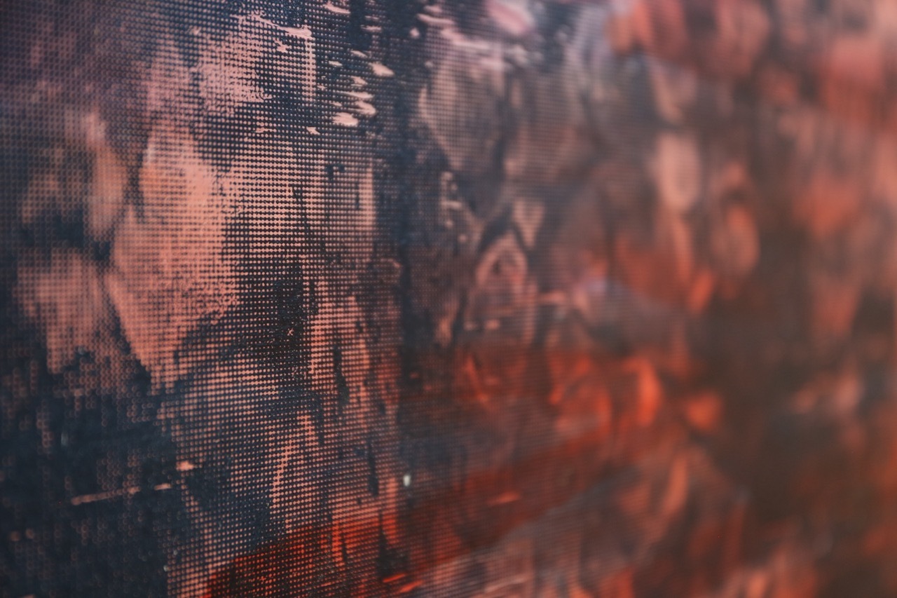 Pixelated digital image with warm orange, pink and red tones blending into darker areas on the left side.